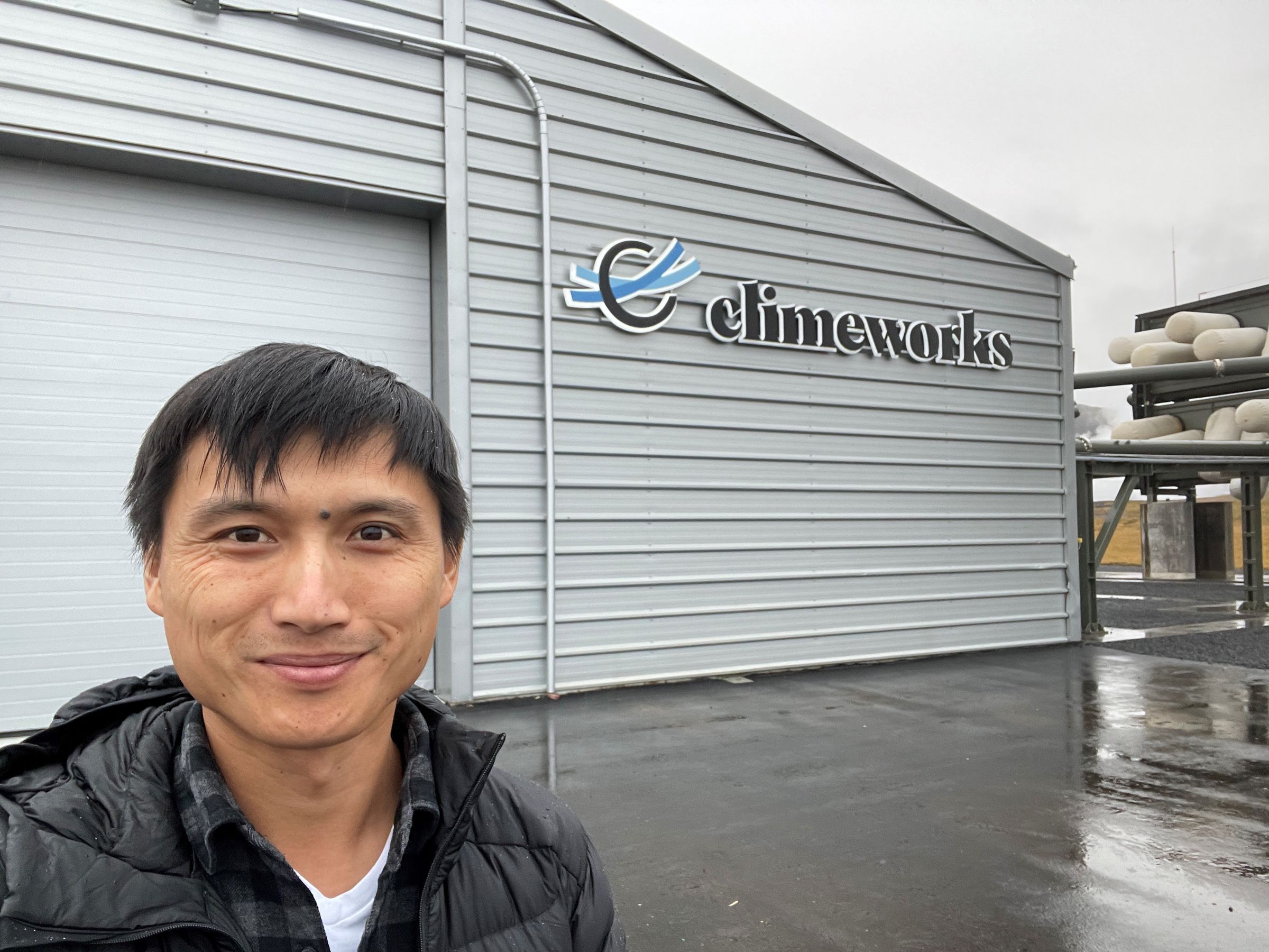 Chan fica na frente de um prédio que diz “Climeworks”.