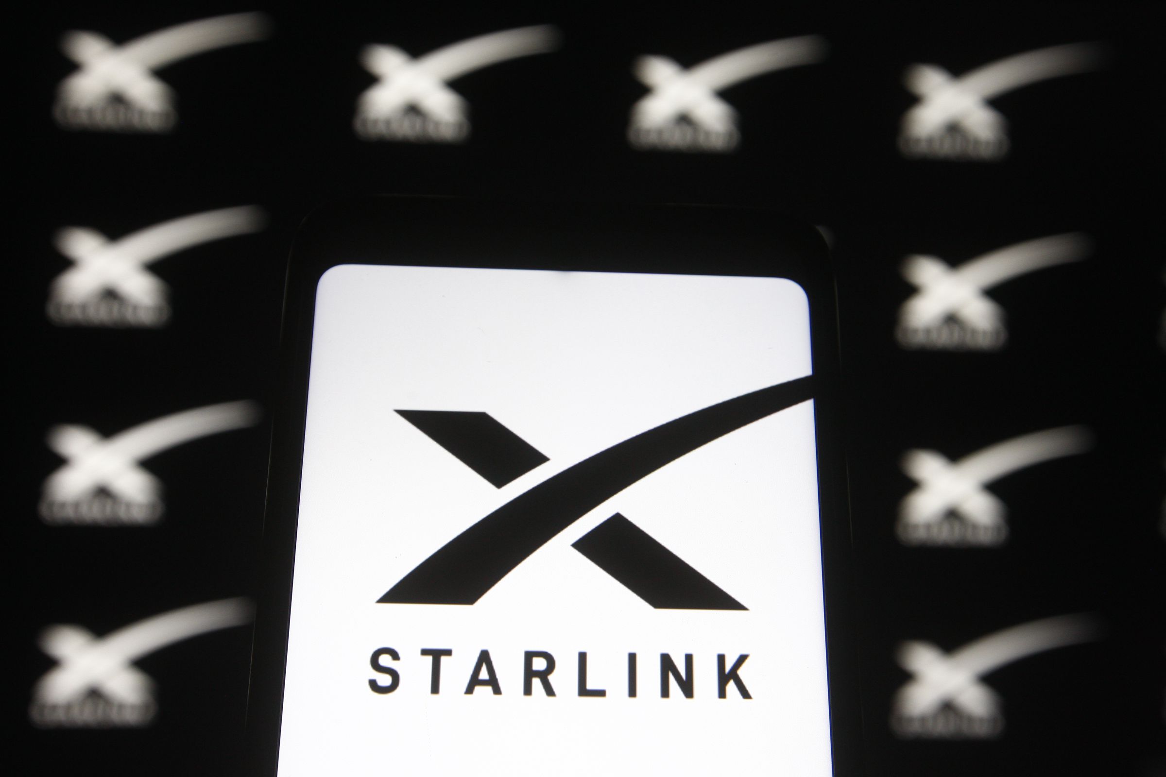 In this photo illustration a Starlink logo of a satellite...