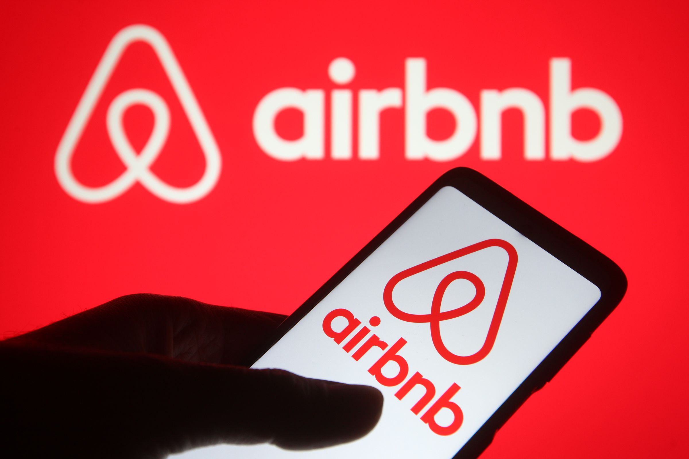 In this photo illustration, an Airbnb logo seen displayed on...