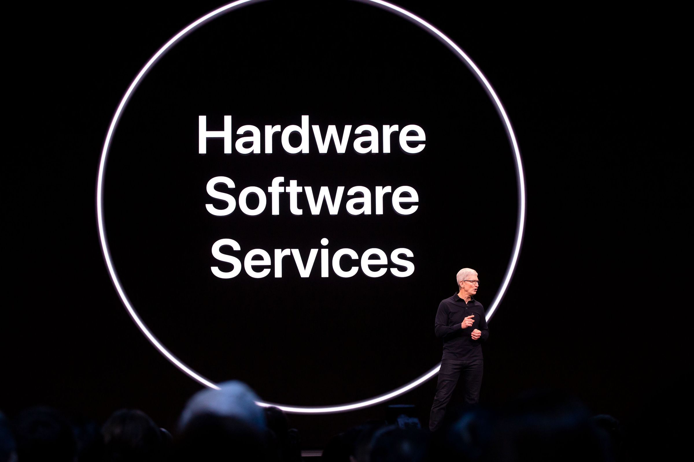 Tim Cook in front of a slide that reads “hardware software services”