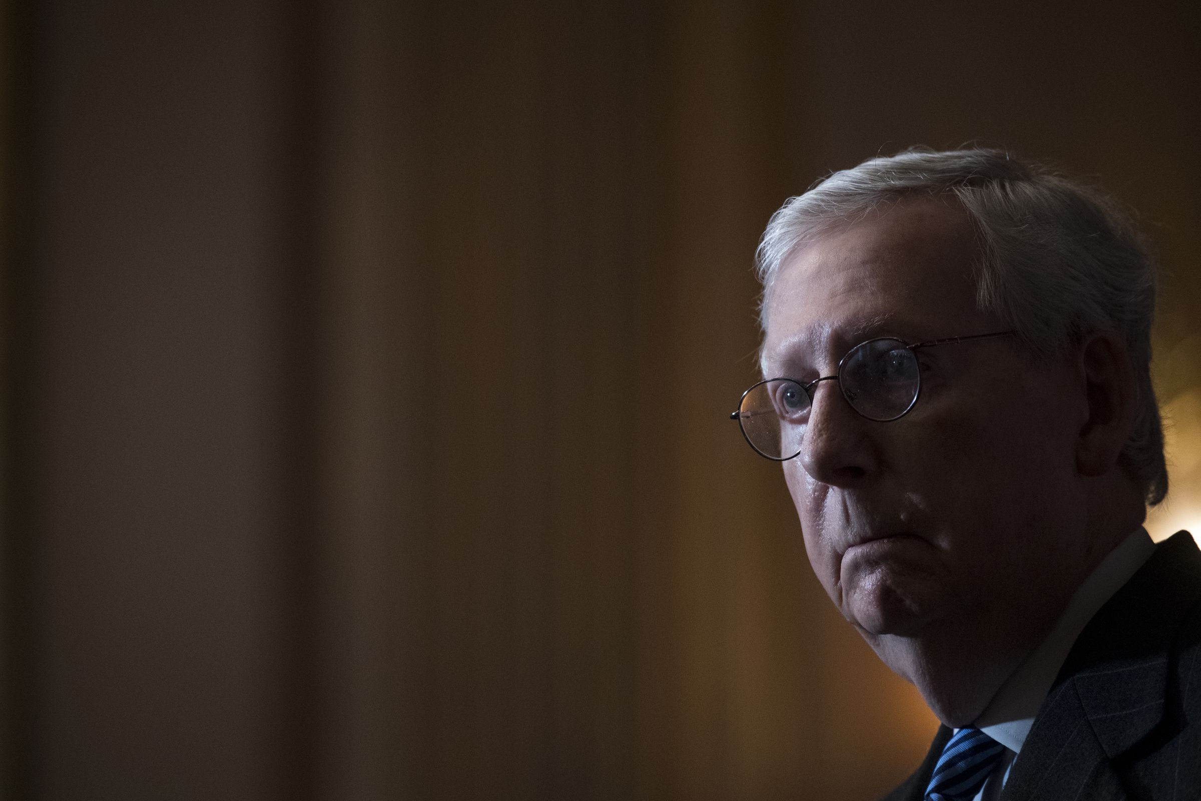 A backlit Mitch McConnell ominously addresses reporters.