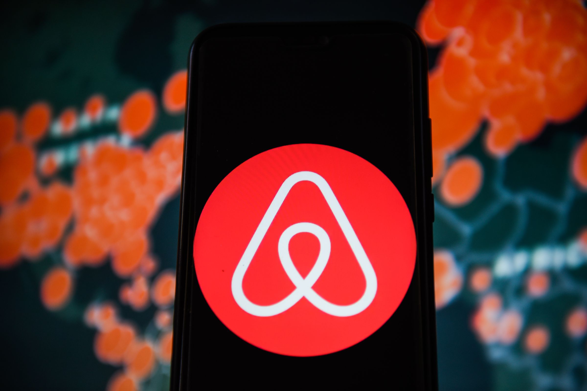 In this photo illustration an Airbnb logo is seen displayed...