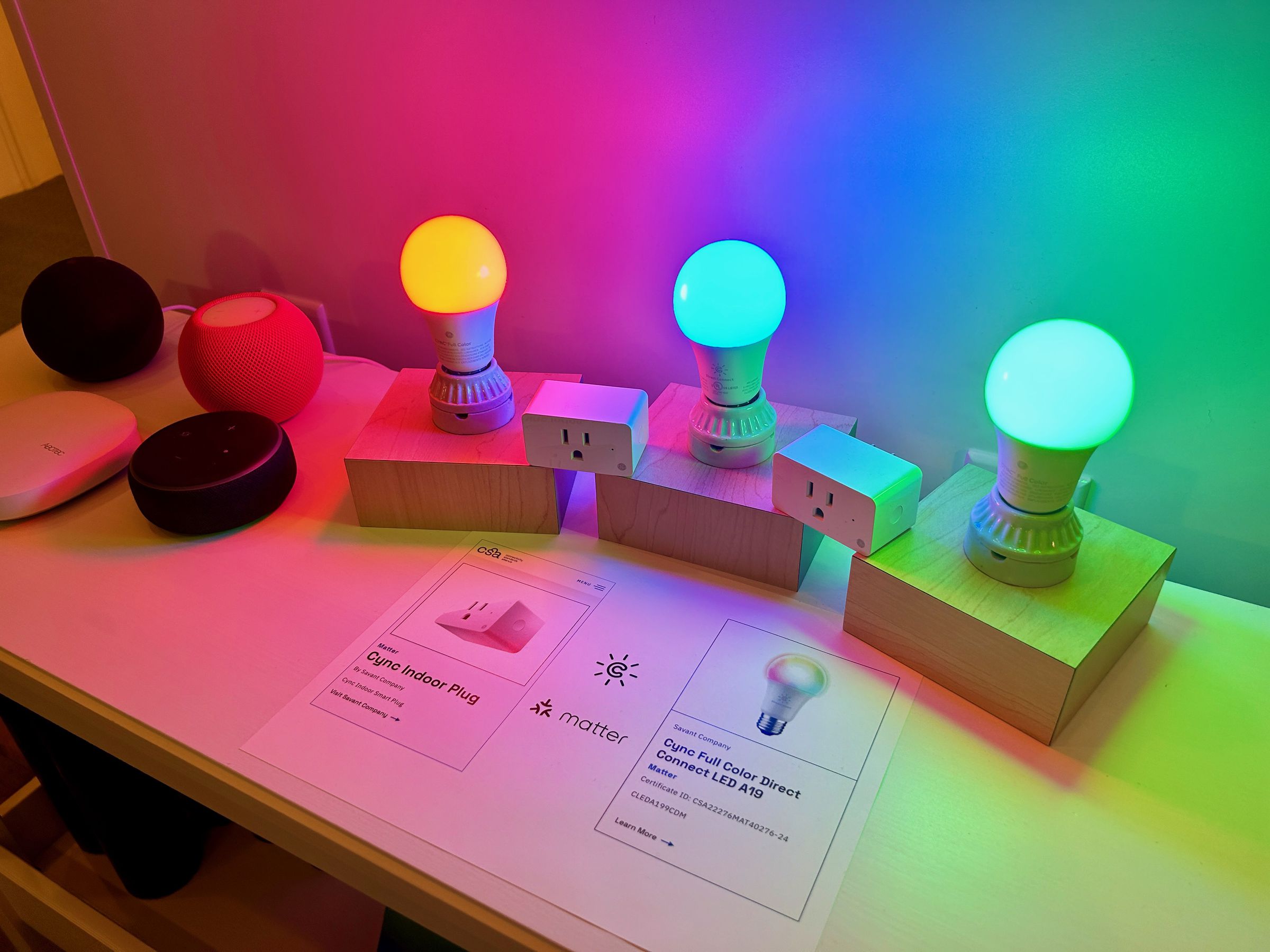 Colored light bulbs and smart plug on a table.