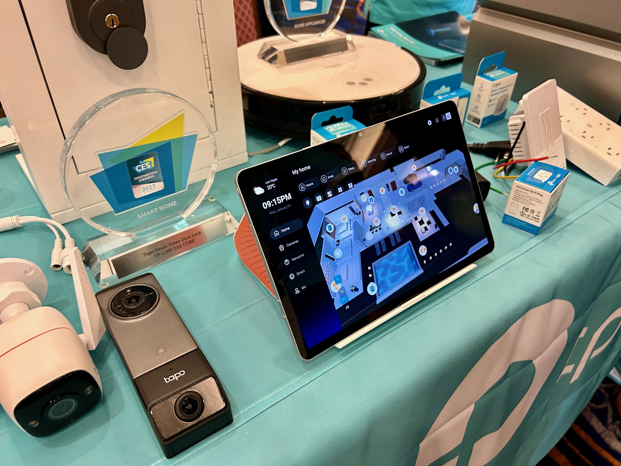 A table of products including cameras, doorbells and a big tablet leaning on an orange hub device.