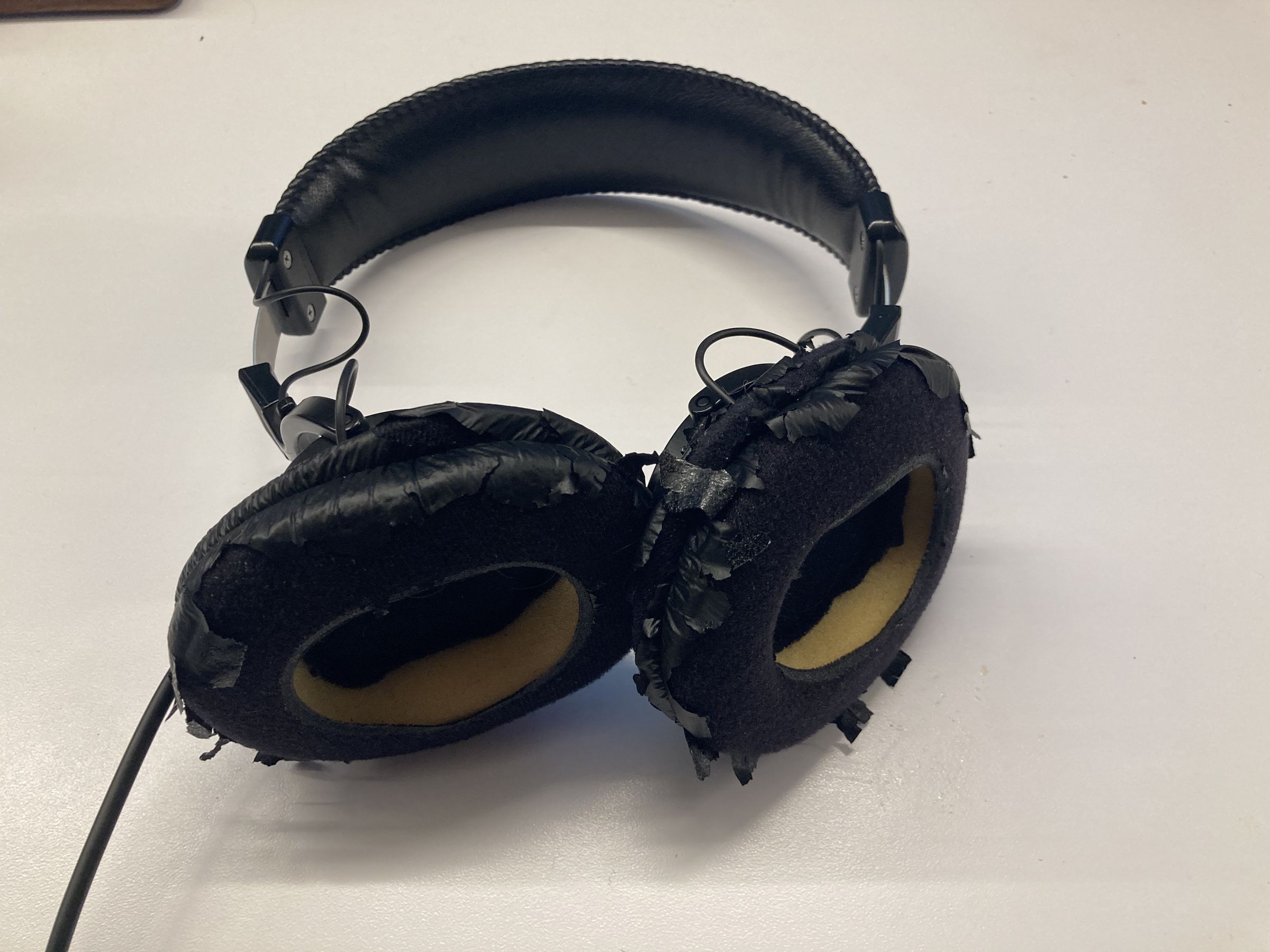 Une paire de Sony MDR-7506 avec des coussinets d'écouteurs très détériorés.