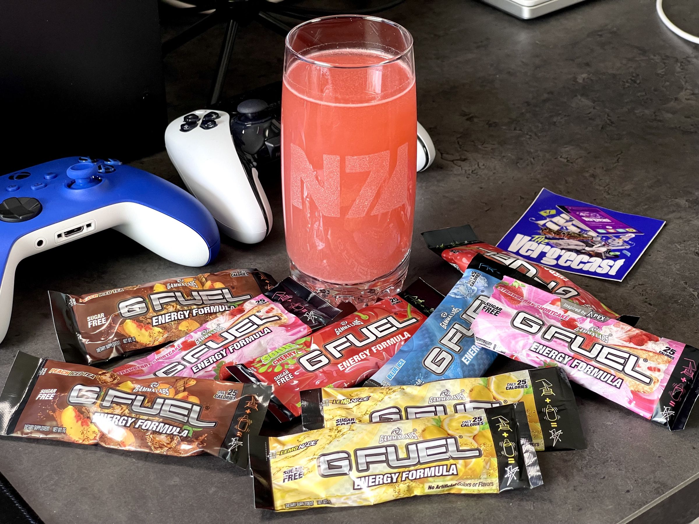 A regretful pile of G Fuel energy drink powders on a desk with a mixed glass of the cursed substance. It looks like the desk of a sad existence.