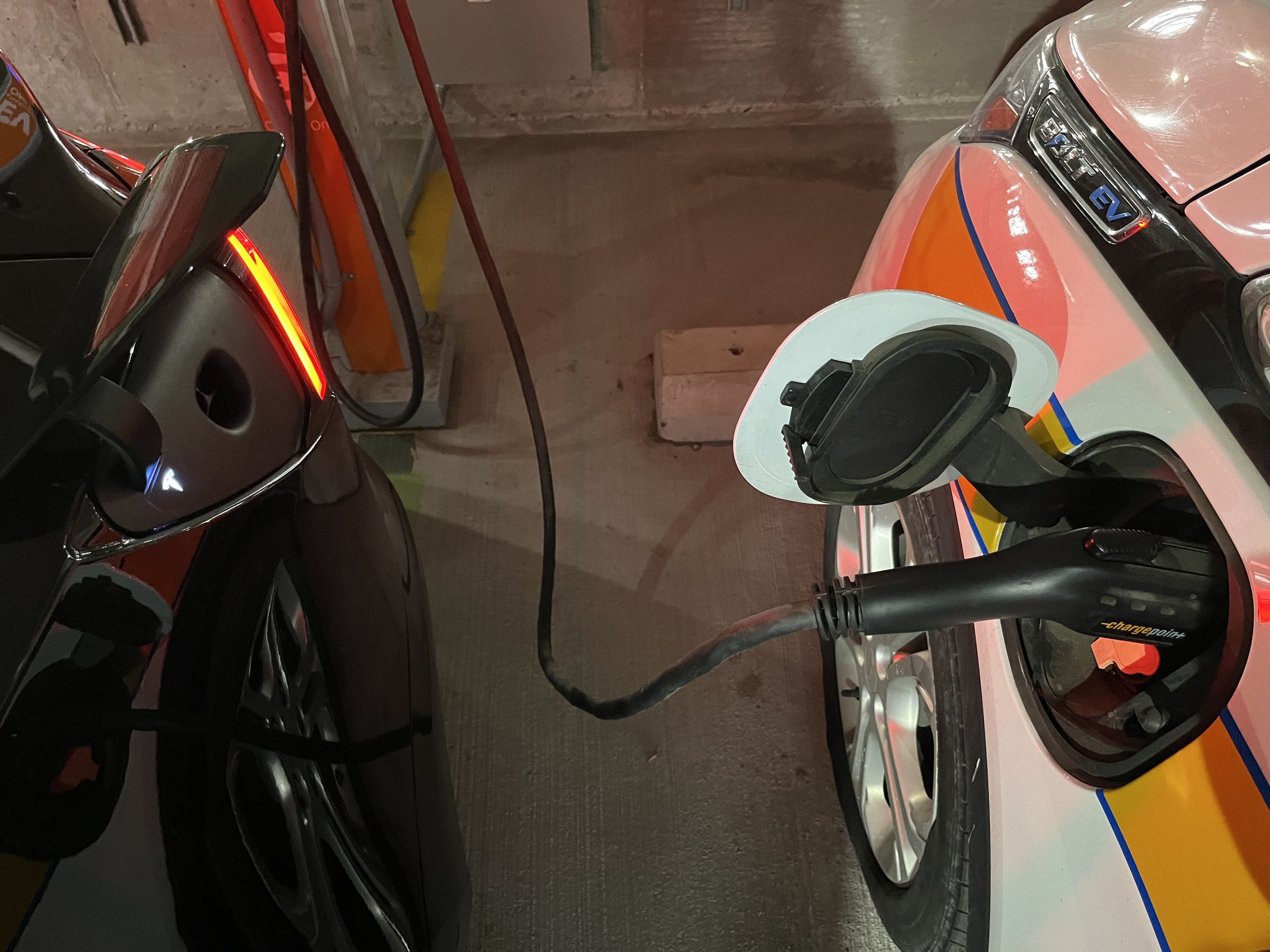 bolt ev port with charge point plug and rear of model 3 with charge door open