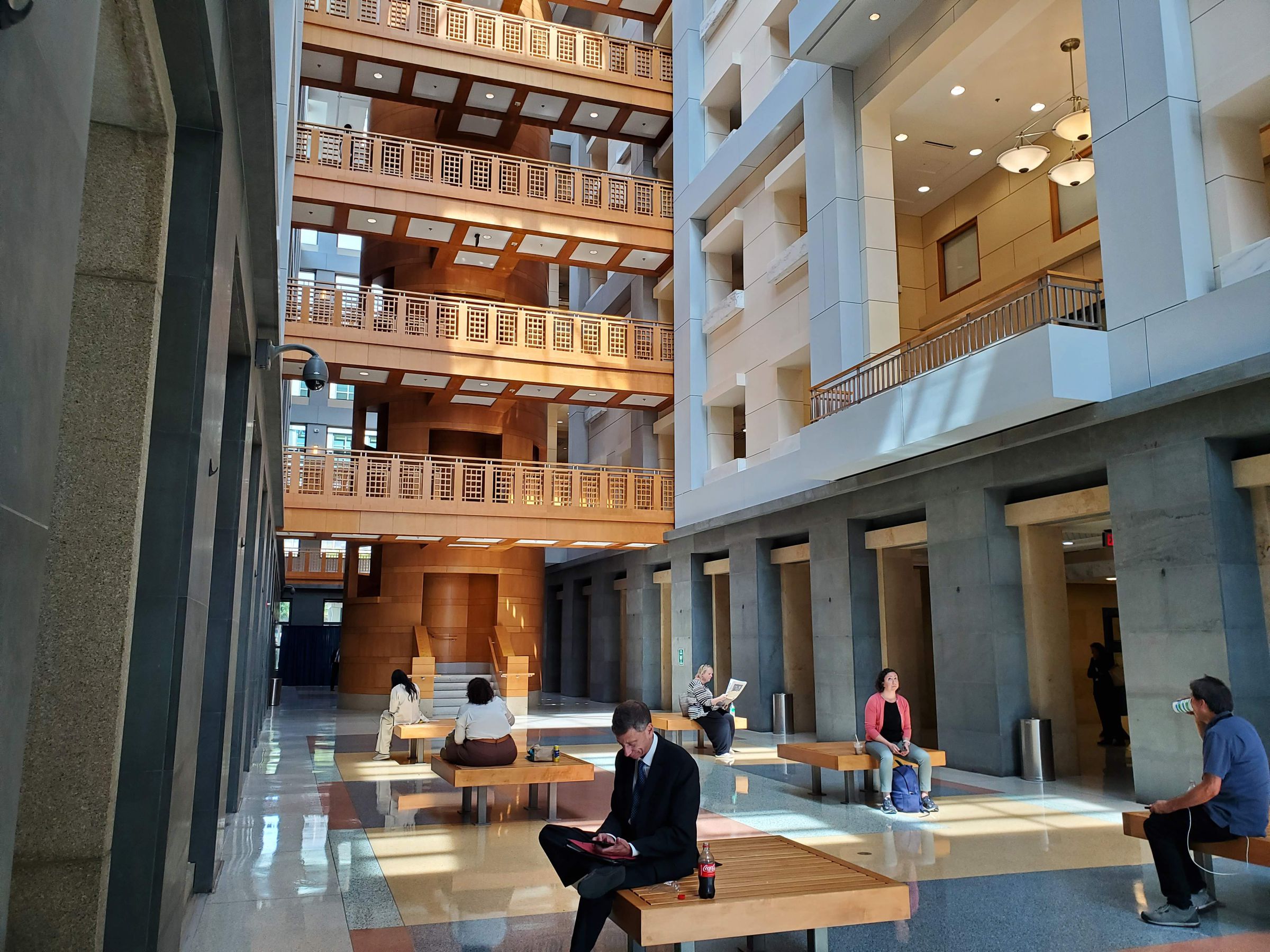 The atrium of the DC federal courthouse, with four floors of wooden balconies and people sitting on benches.