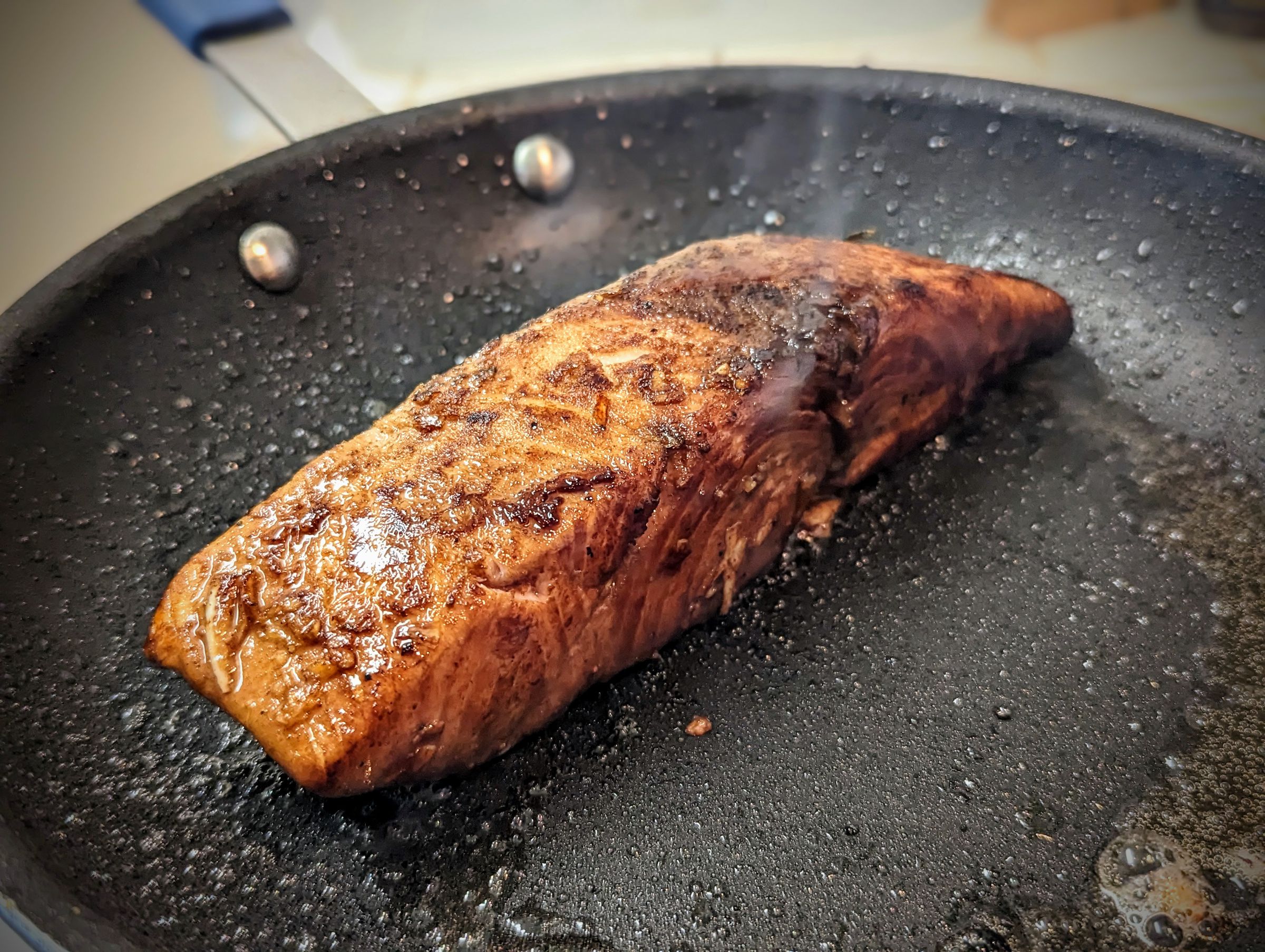 Searing a piece of salmon in a frying pan after cooking it with the Joule Turbo.