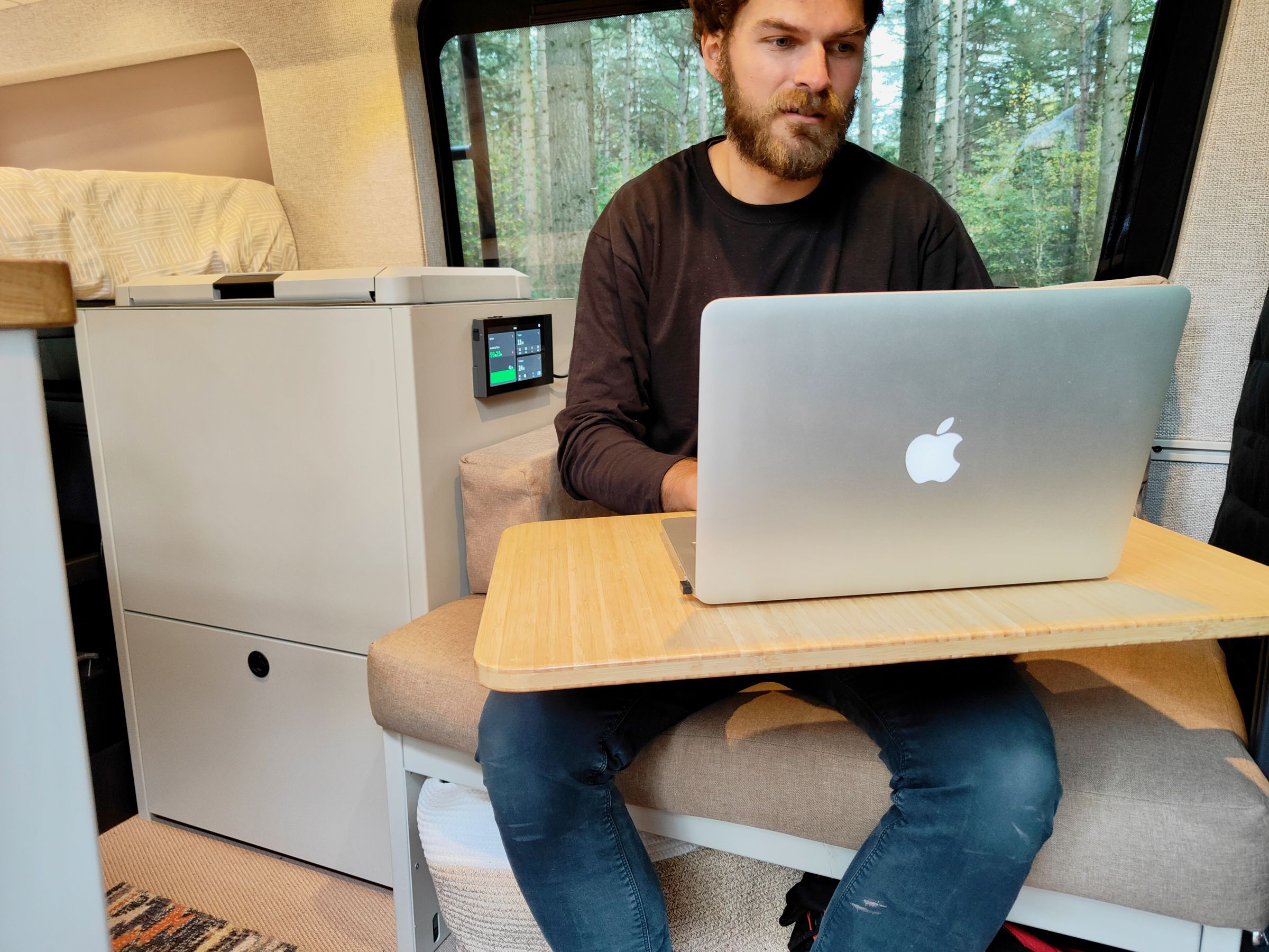 Fabian working from his van with the EcoFlow console showing charge status behind him.