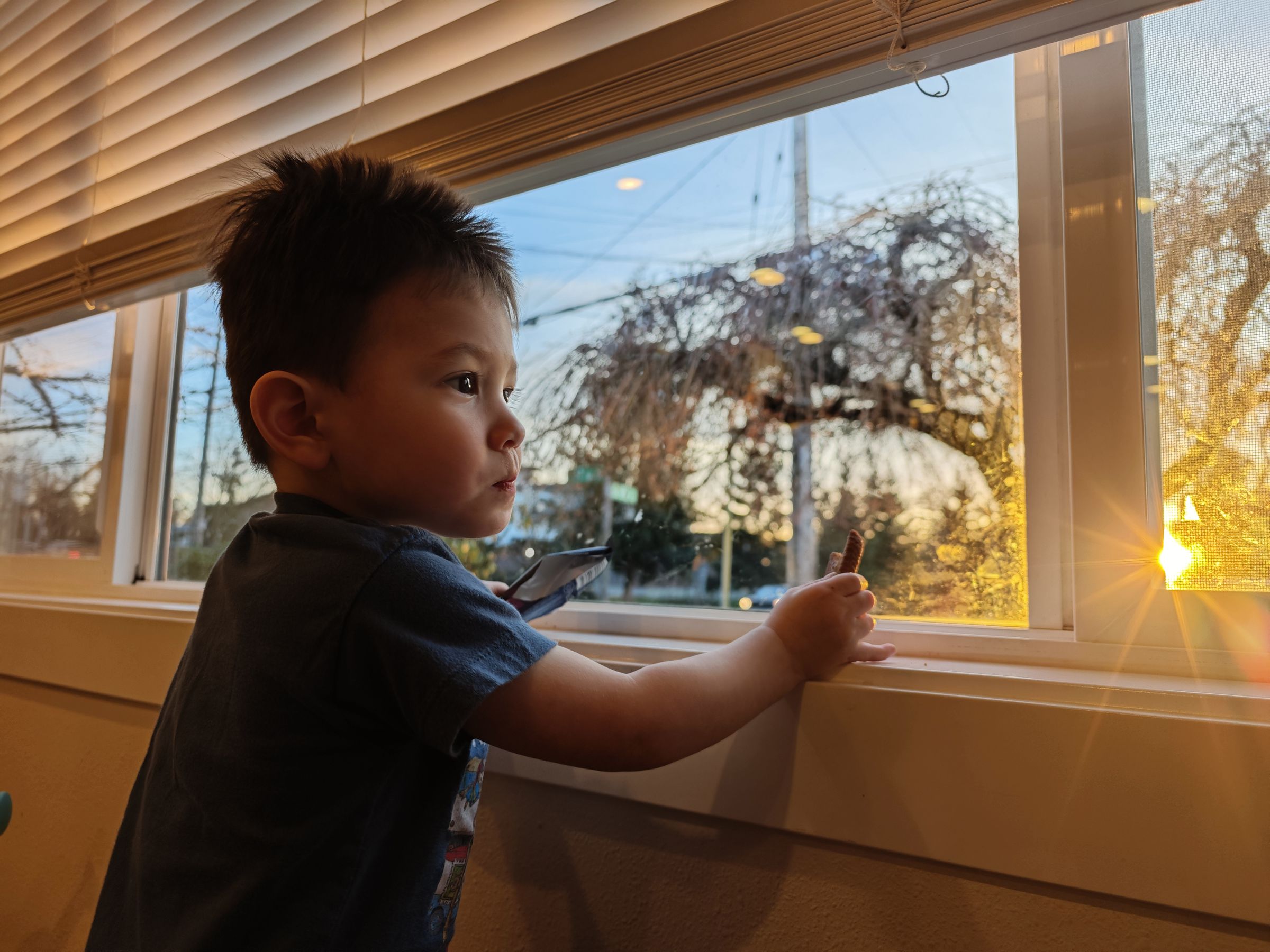 Photo of a young child at a window with sunstar in corner of the frame.