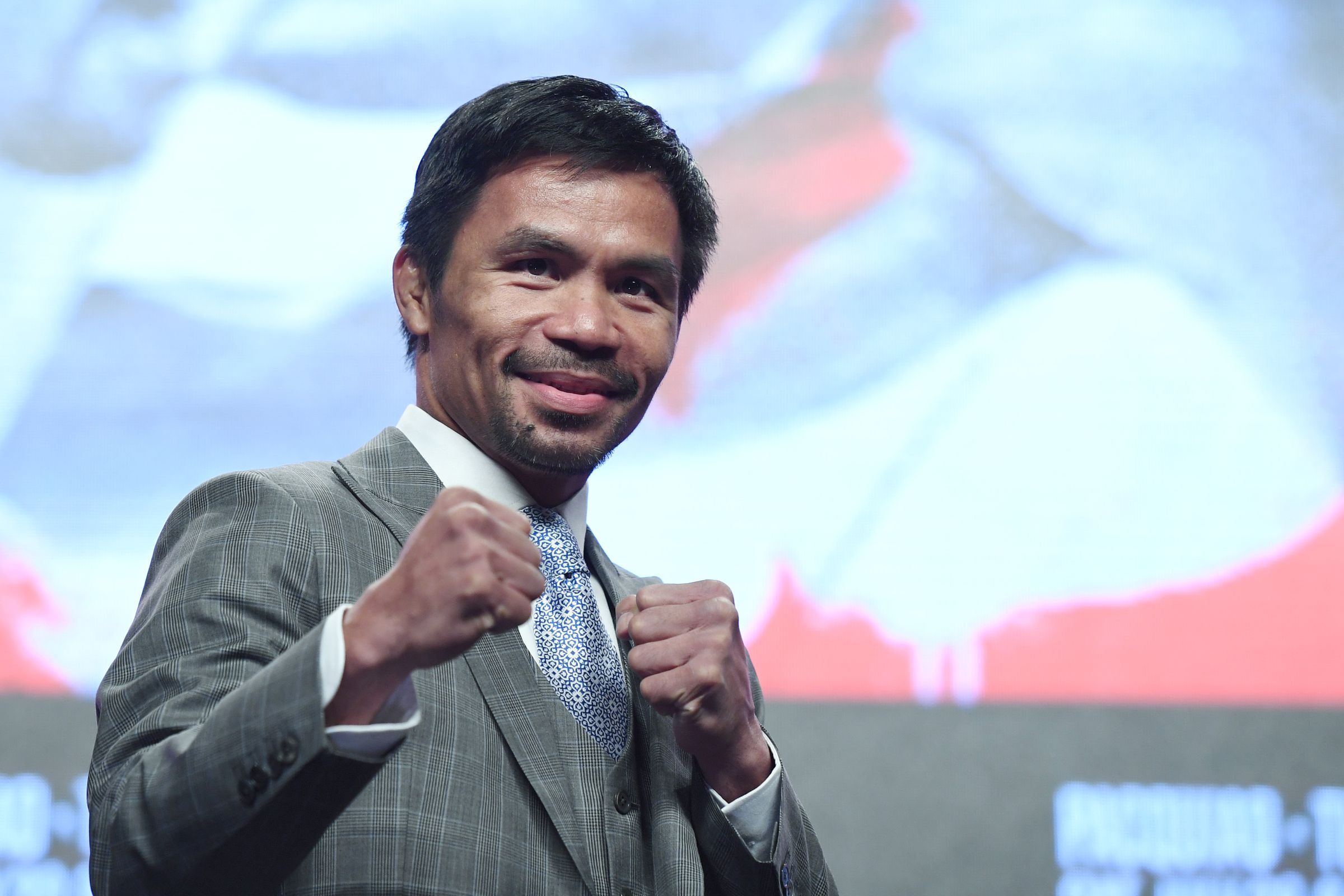 Manny Pacquiao poses with raised fists wearing a gray wool suit.