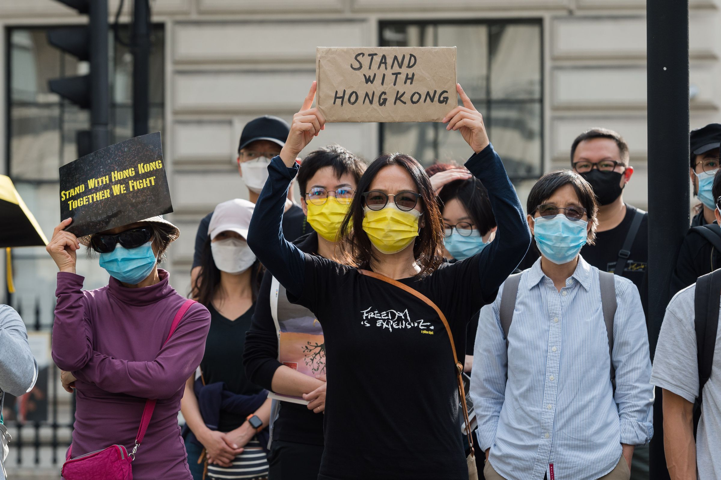 A crowd of people wearing facemasks hold up signs in support of Hong Kong.
