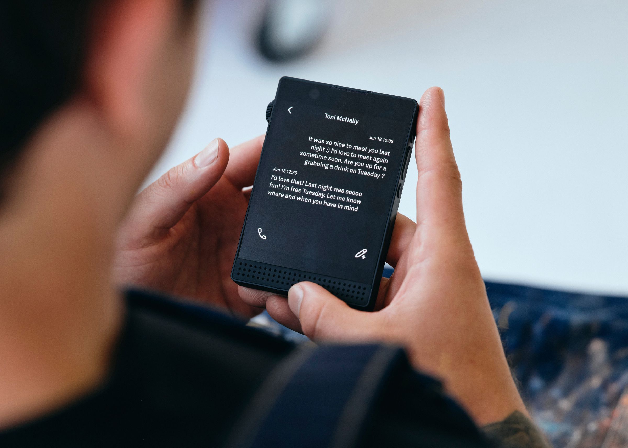 A photo of a person texting on a Light Phone 3.