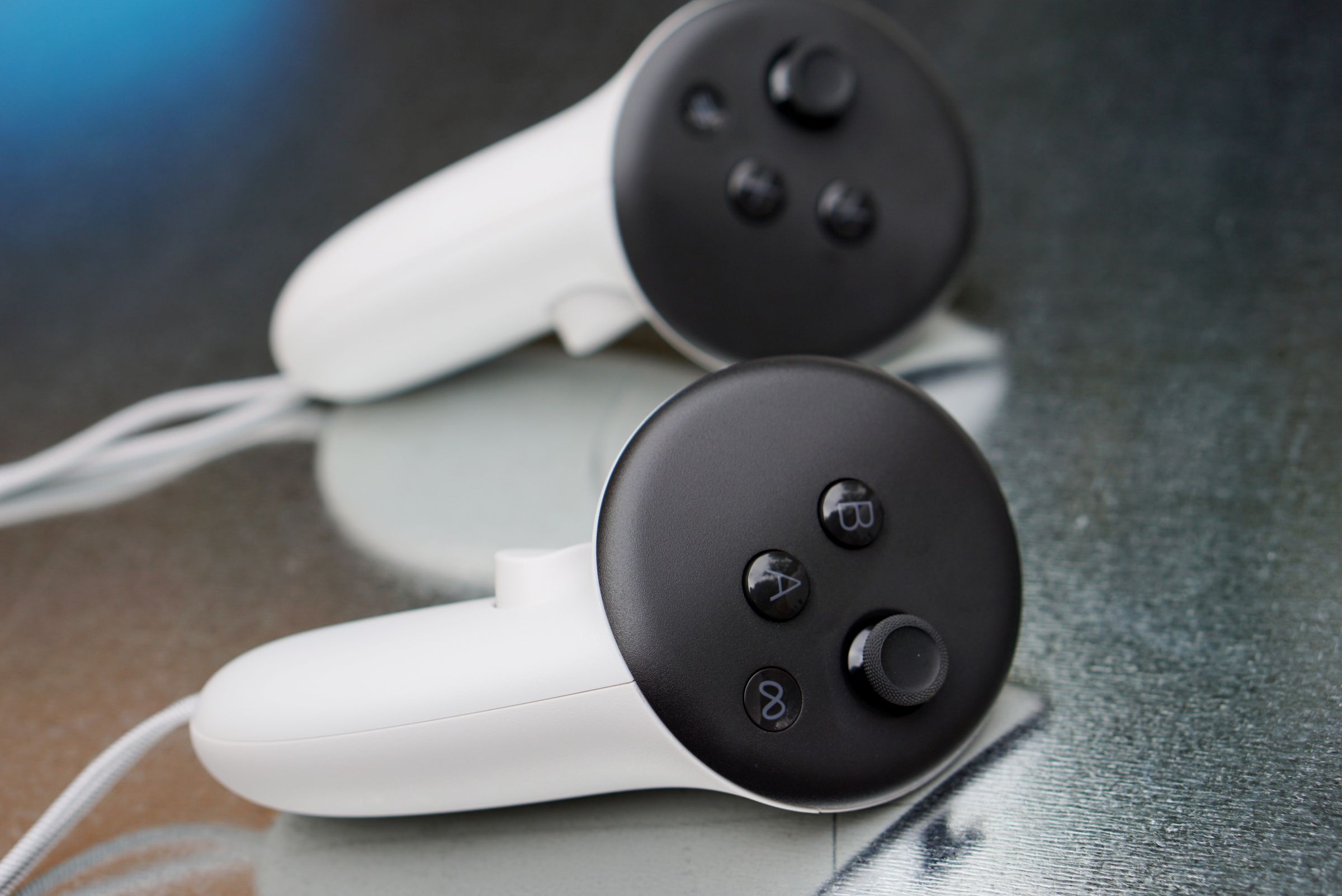 A photo of two white controllers on a shiny metal background.