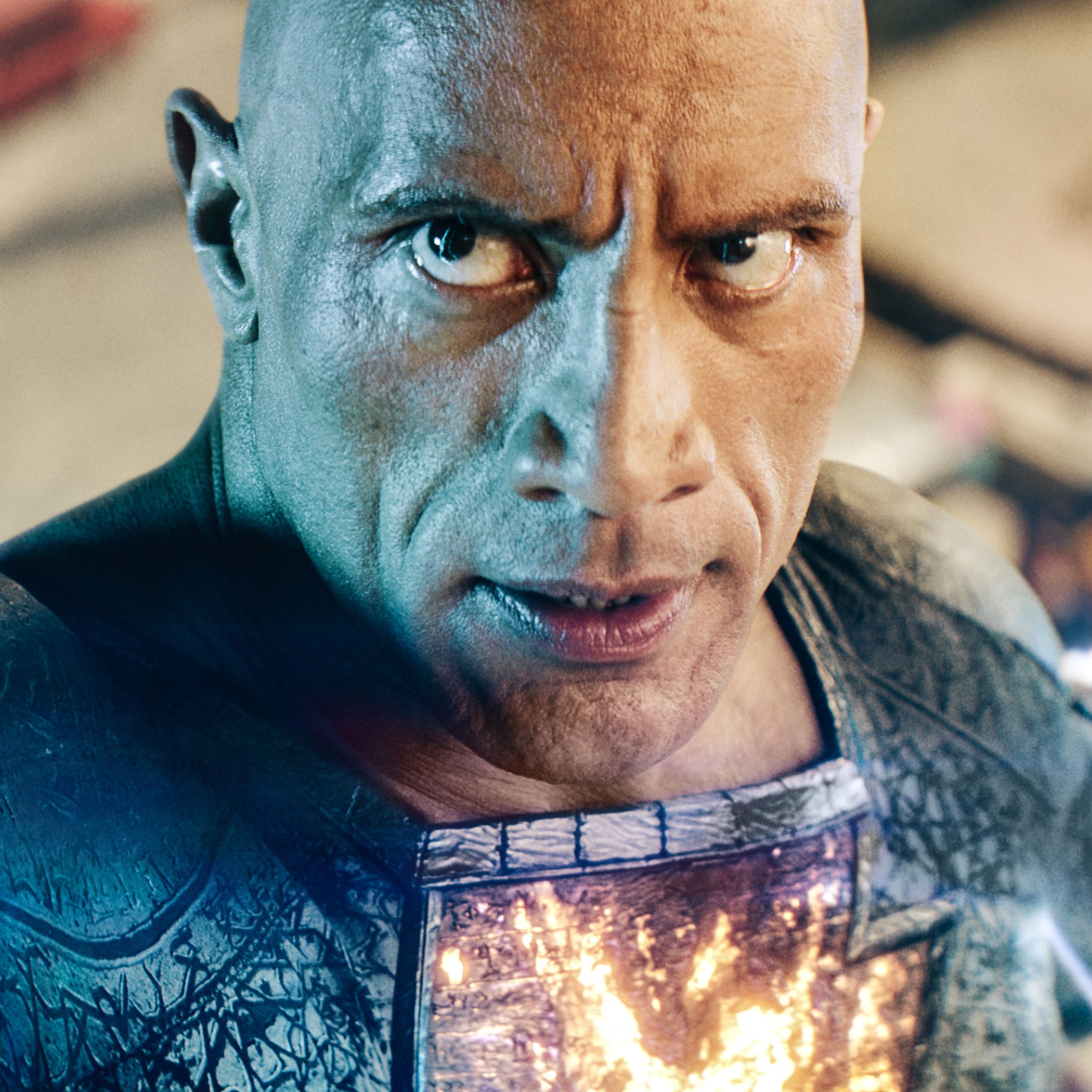 A tight shot of a bald man in a black superhero suit with lightning crawling up his left arm to shoot out of his right, which is reaching beyond the camera’s view.