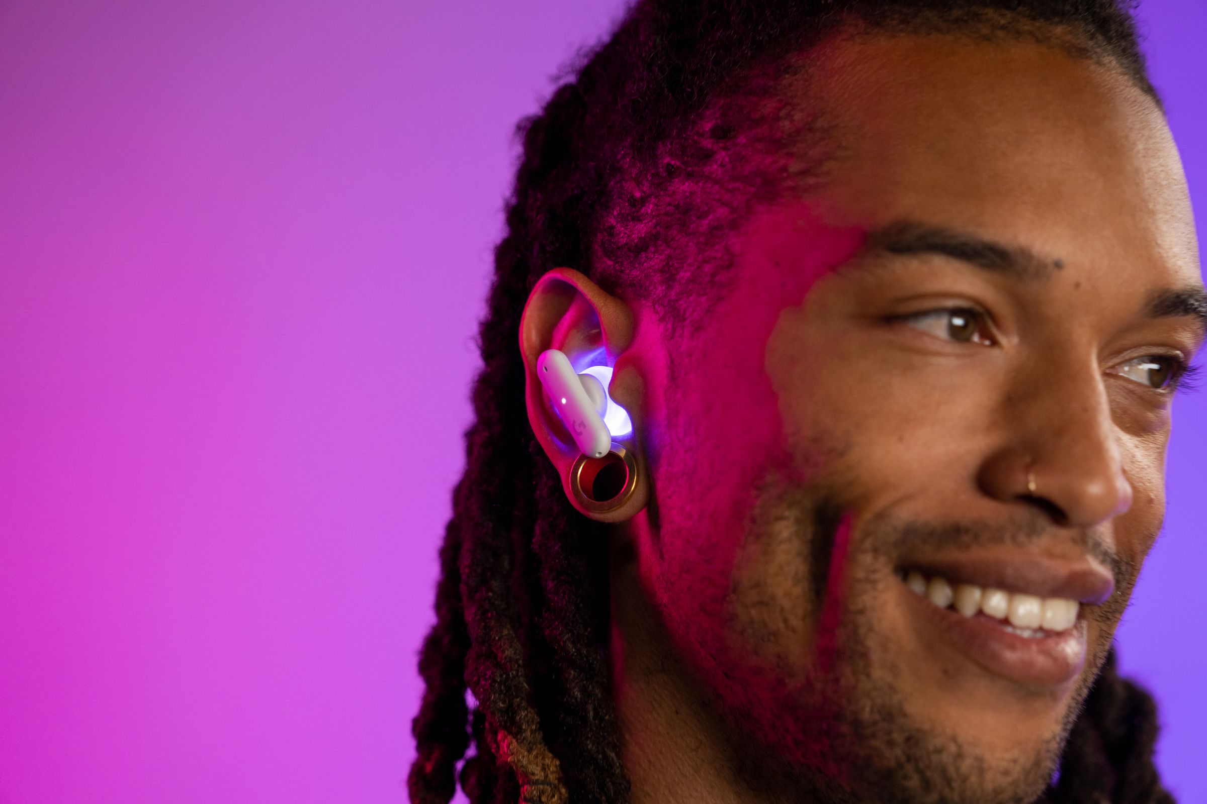 A model turning to the side, smiling, while wearing the Logitech G Fits earbuds