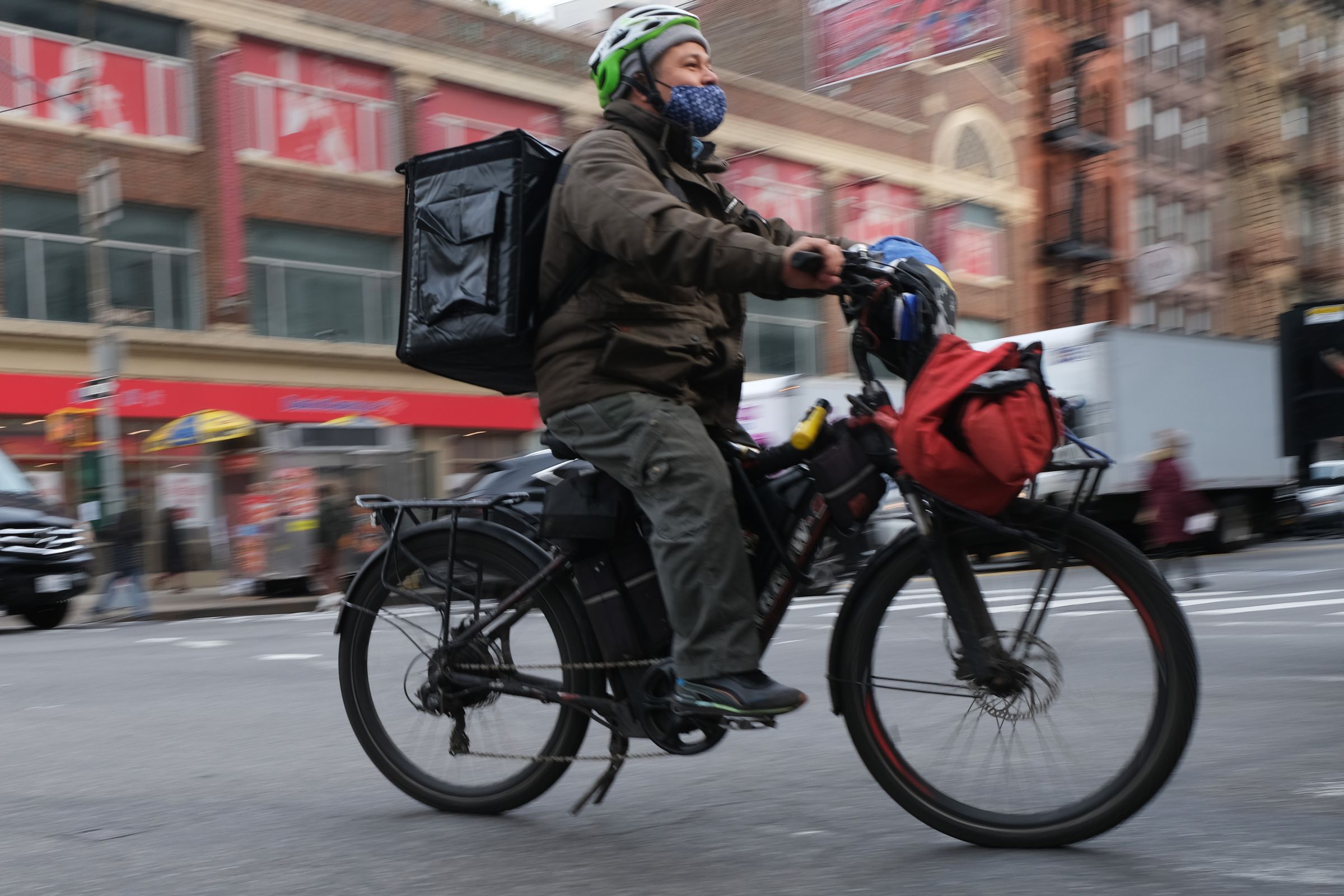 A delivery worker with a package on their back rides an e-bike in Manhattan in New York City.