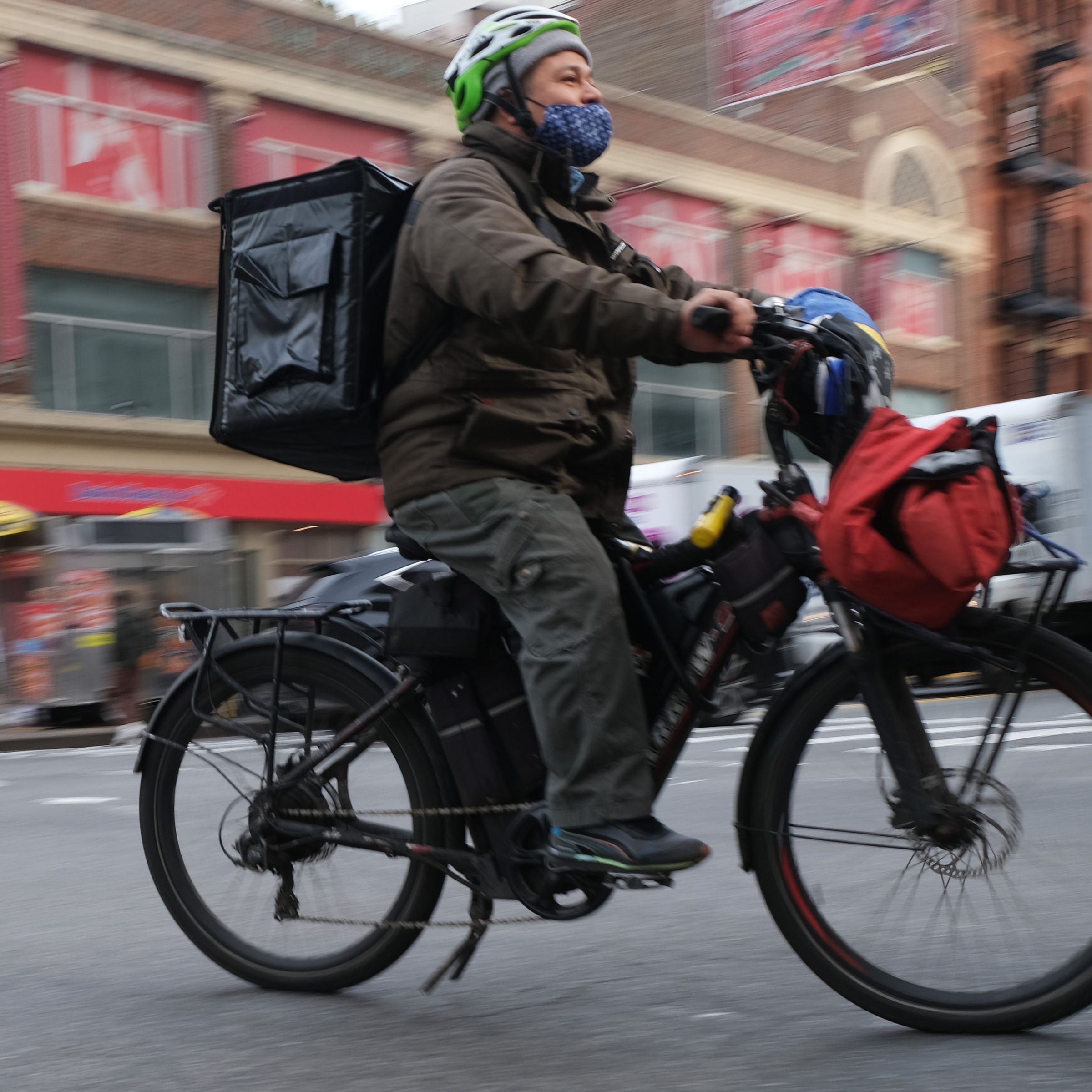 A delivery worker with a package on their back rides an e-bike in Manhattan in New York City.