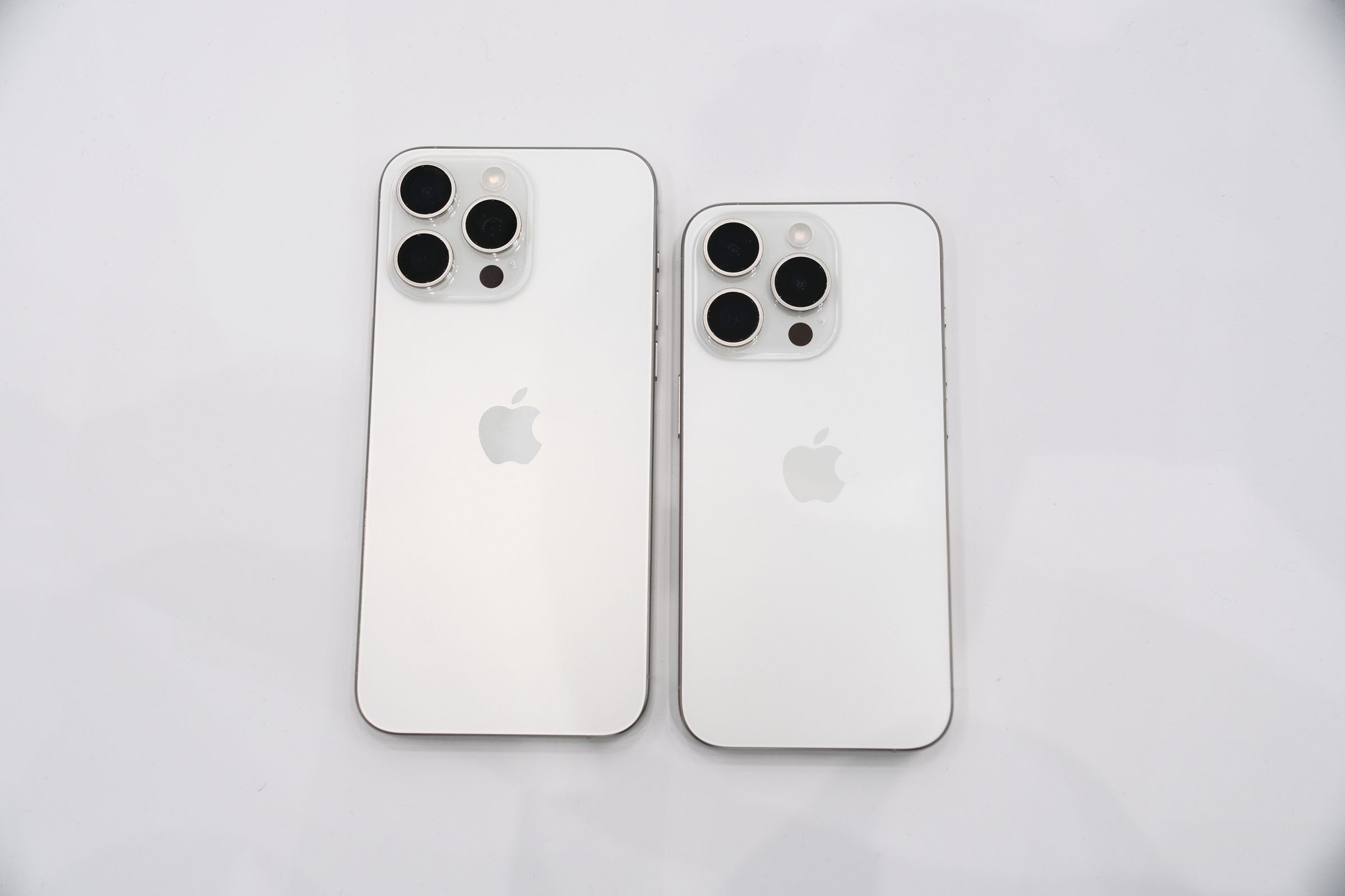 Apple iPhone 15 Pro and 15 Pro Max in white titanium.