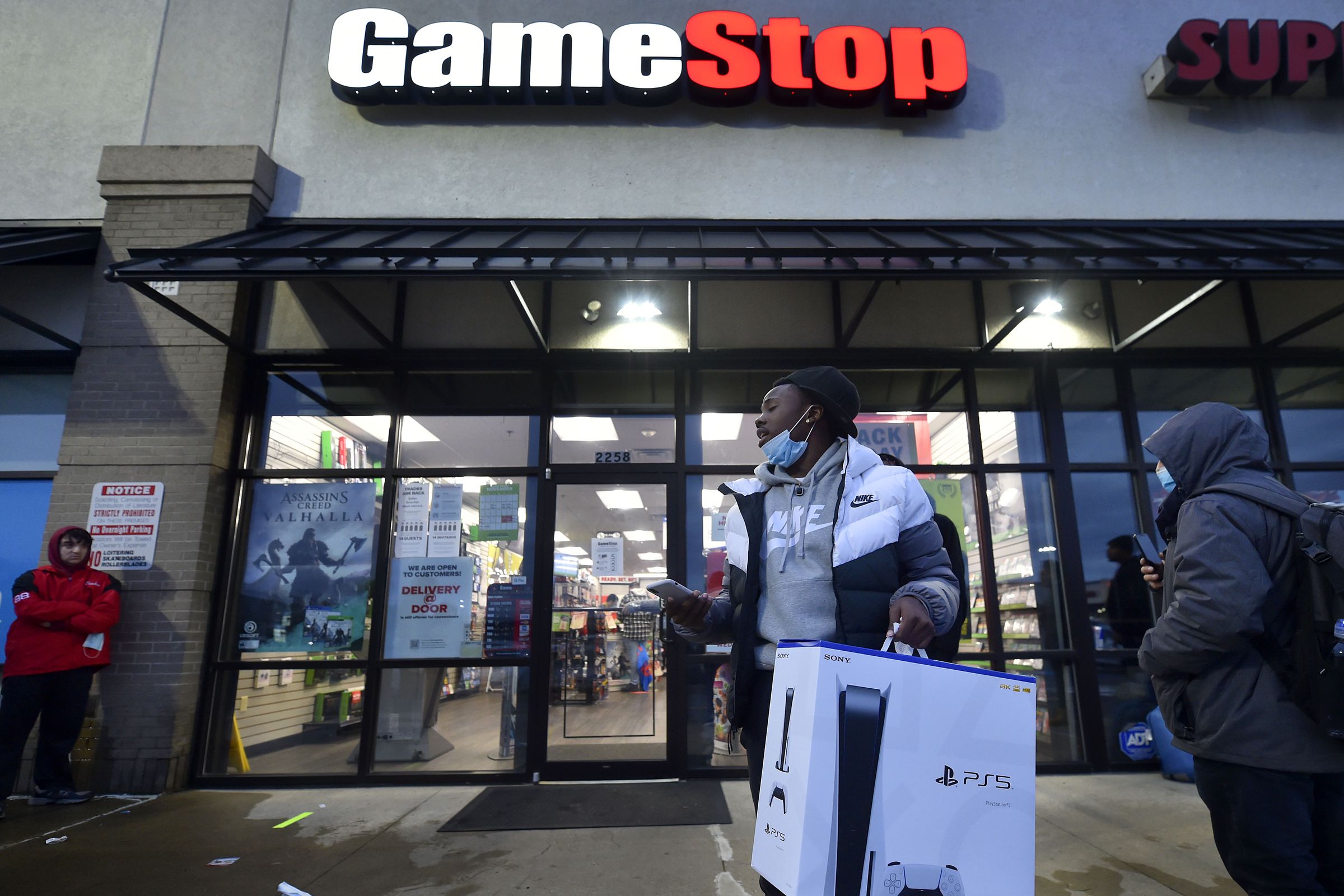 A man wearing a face mask leaves Game Stop with the new...