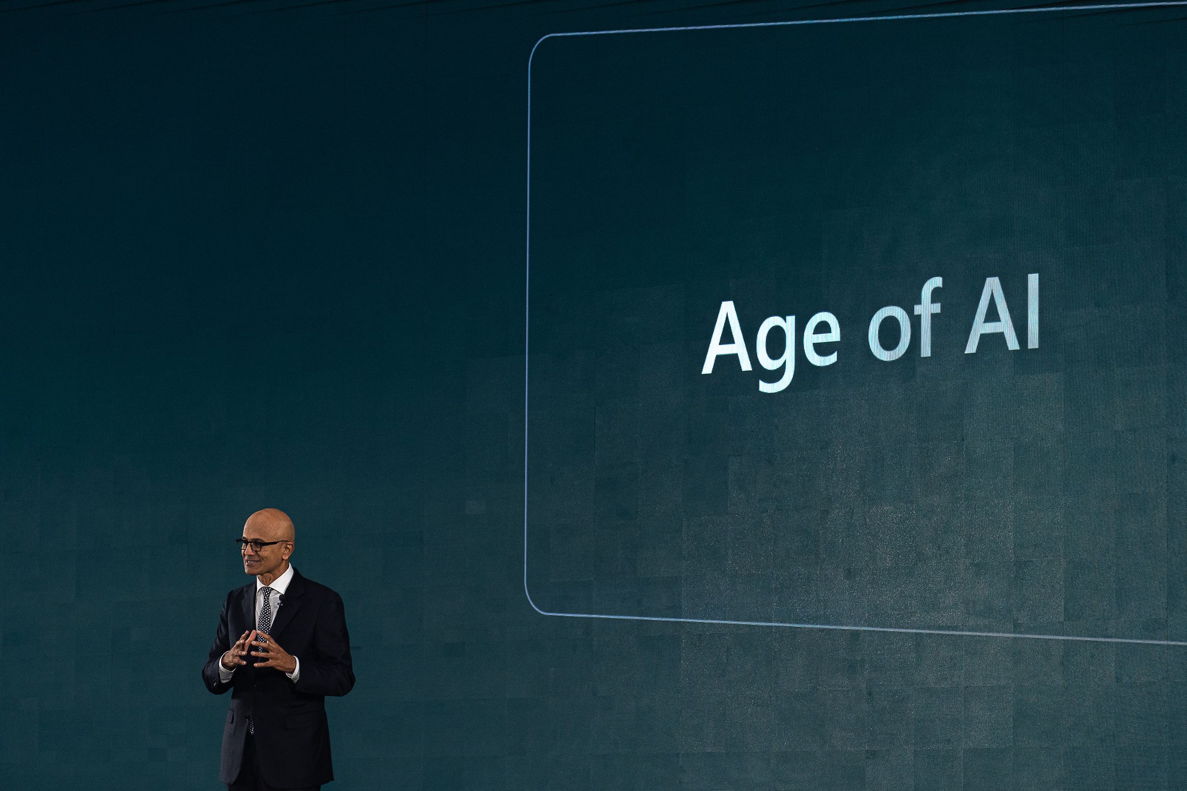 A man speaks in front of a screen that says “Age of AI”