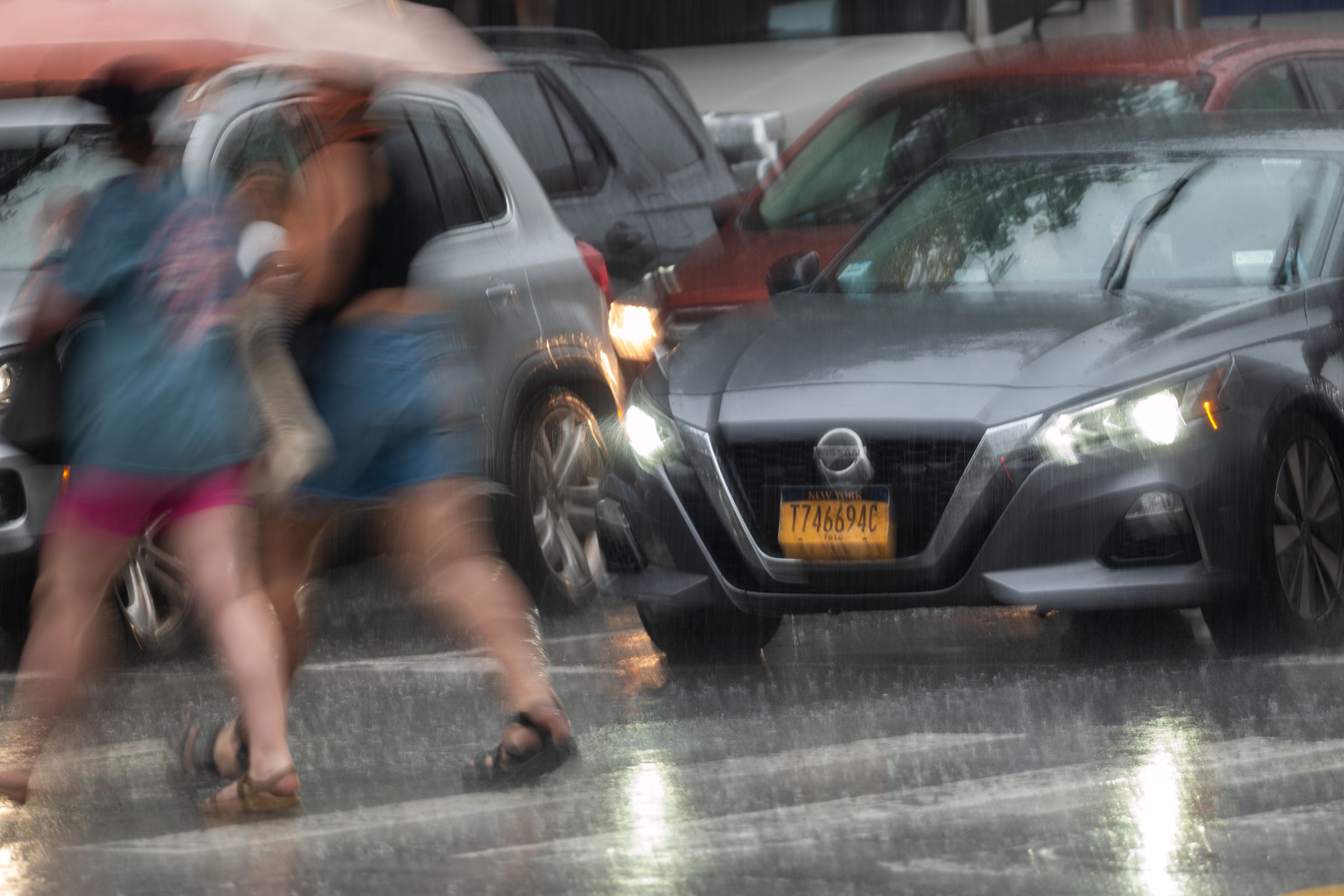 Pedestrians and cars move through midtown Manhattan traffic.