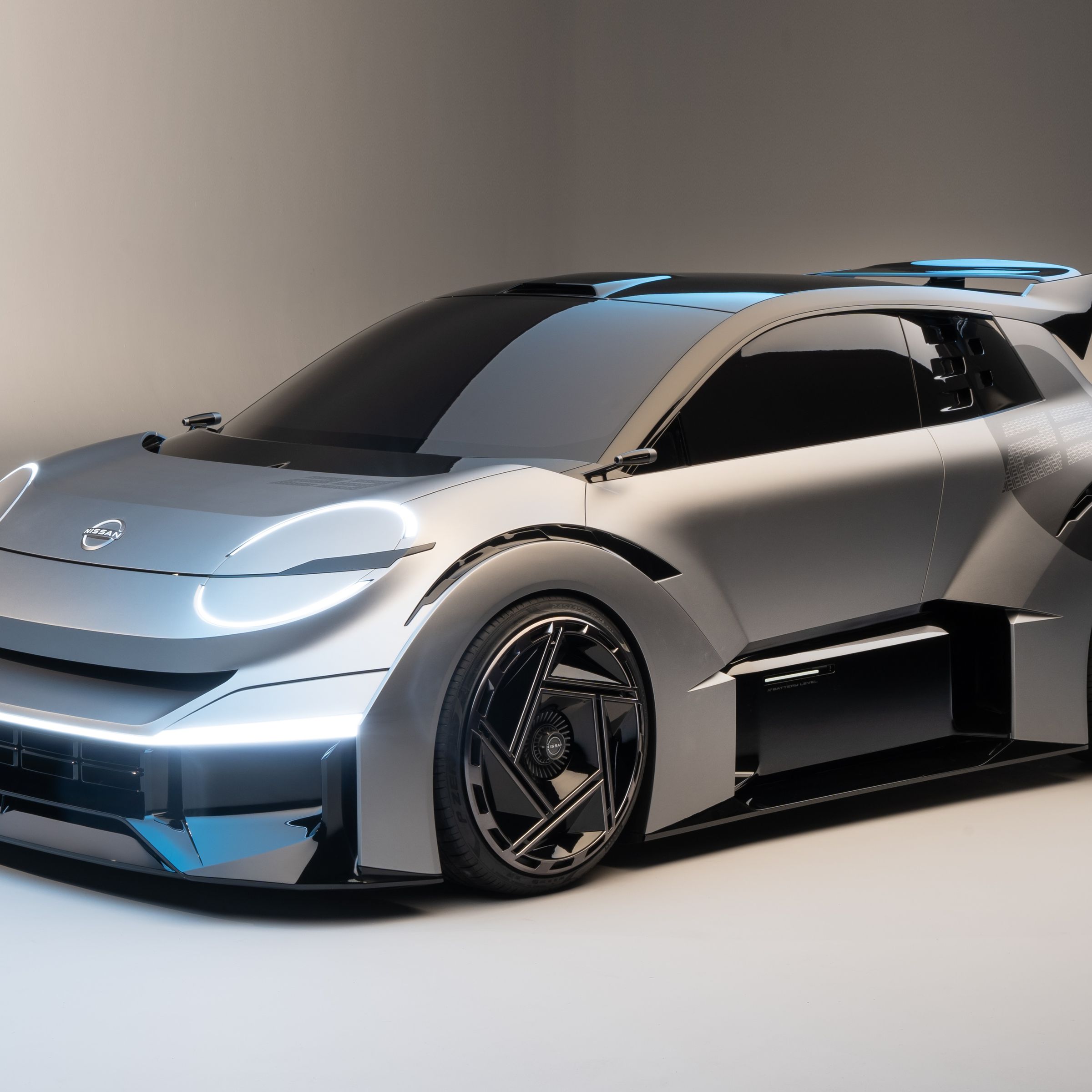 Render of a micro Machines-looking car from Nissan, has circle-outlined daytime running lights and a large spoiler on the top of the rear hatch, and it’s low with really big rims.