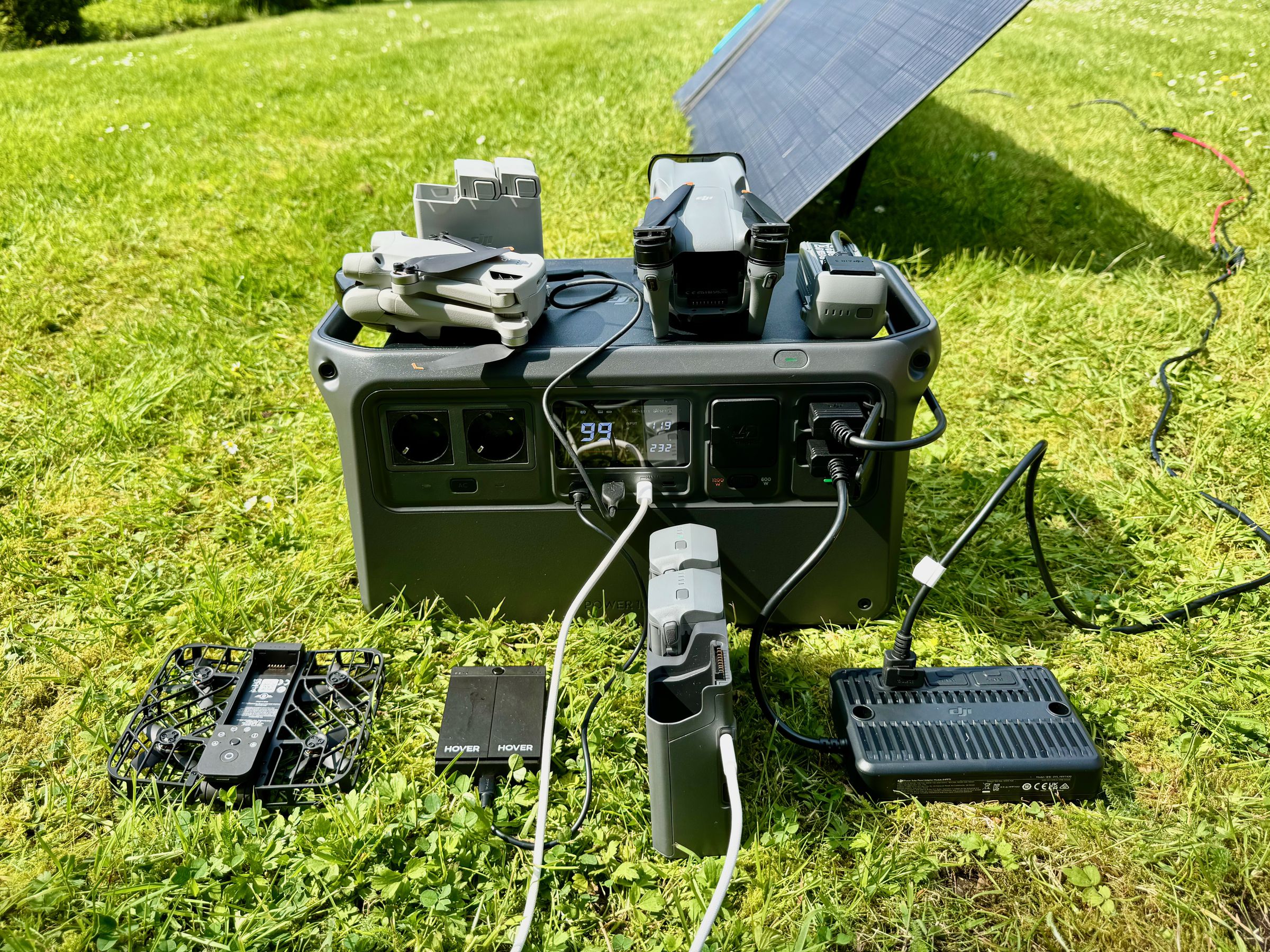 <em>The HoverAir and its tiny batteries charging next to a DJI Mini 3 Pro and DJI Air 3 on a DJI power station.</em>