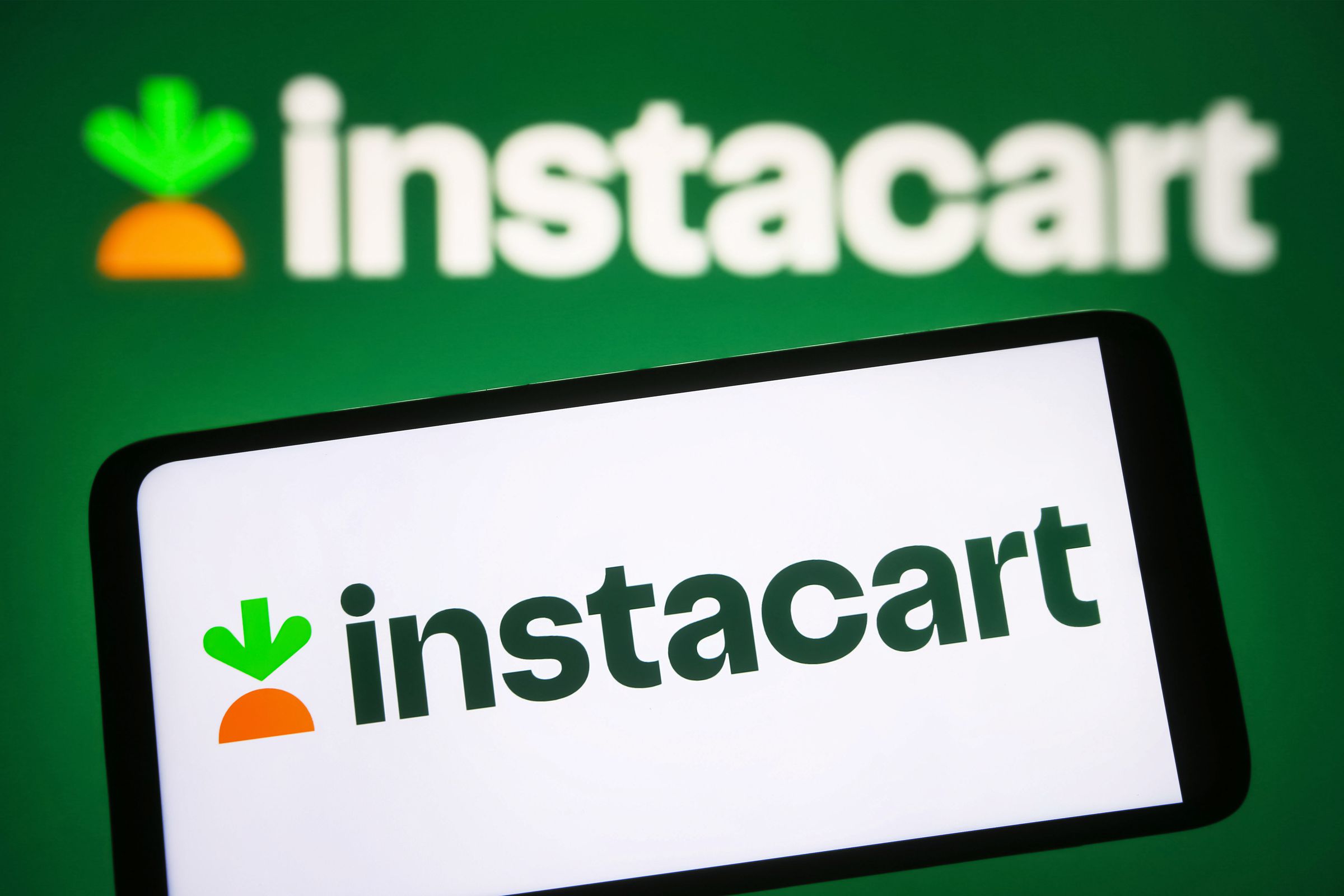 Instacart logo is seen on a phone screen against a green background 