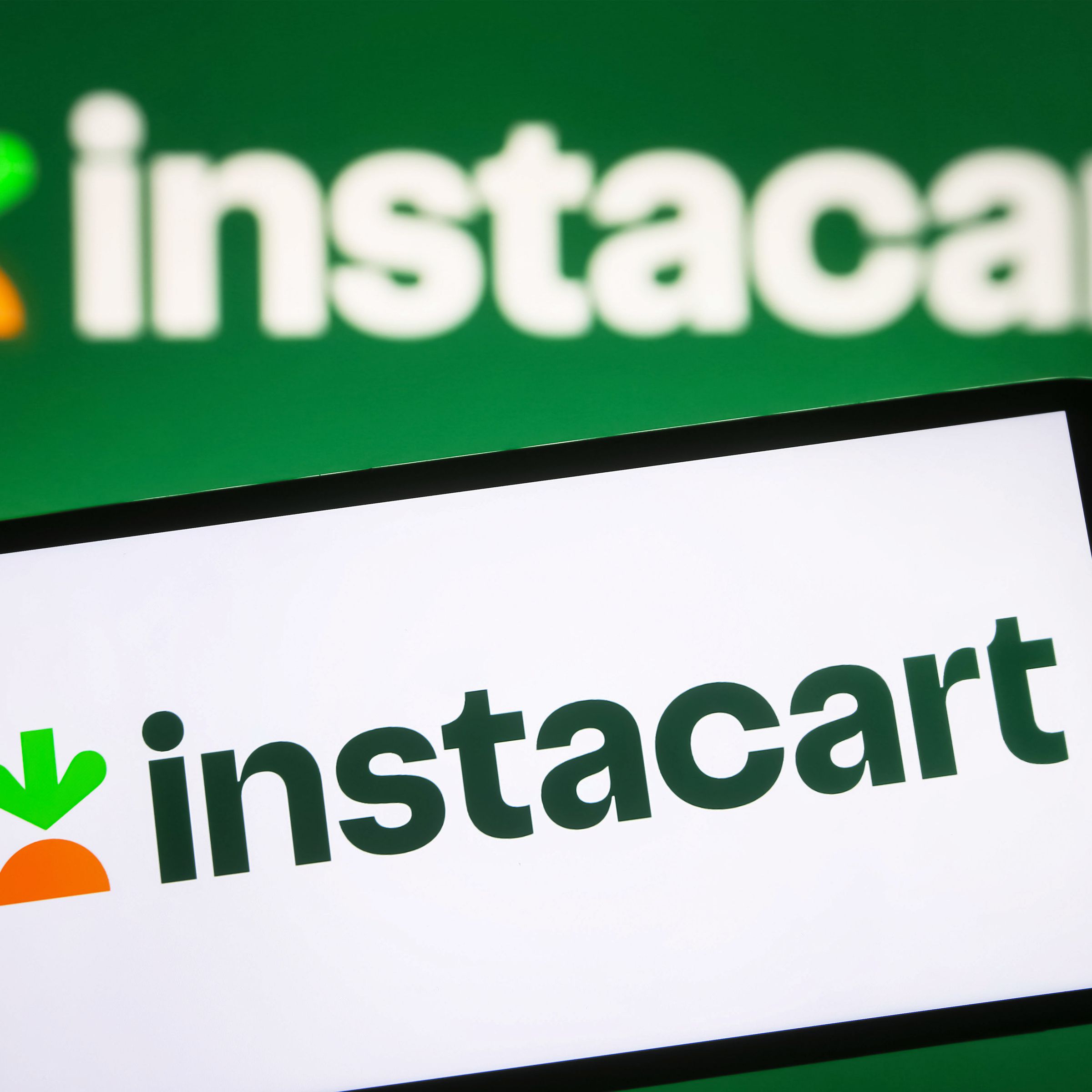 Instacart logo is seen on a phone screen against a green background 