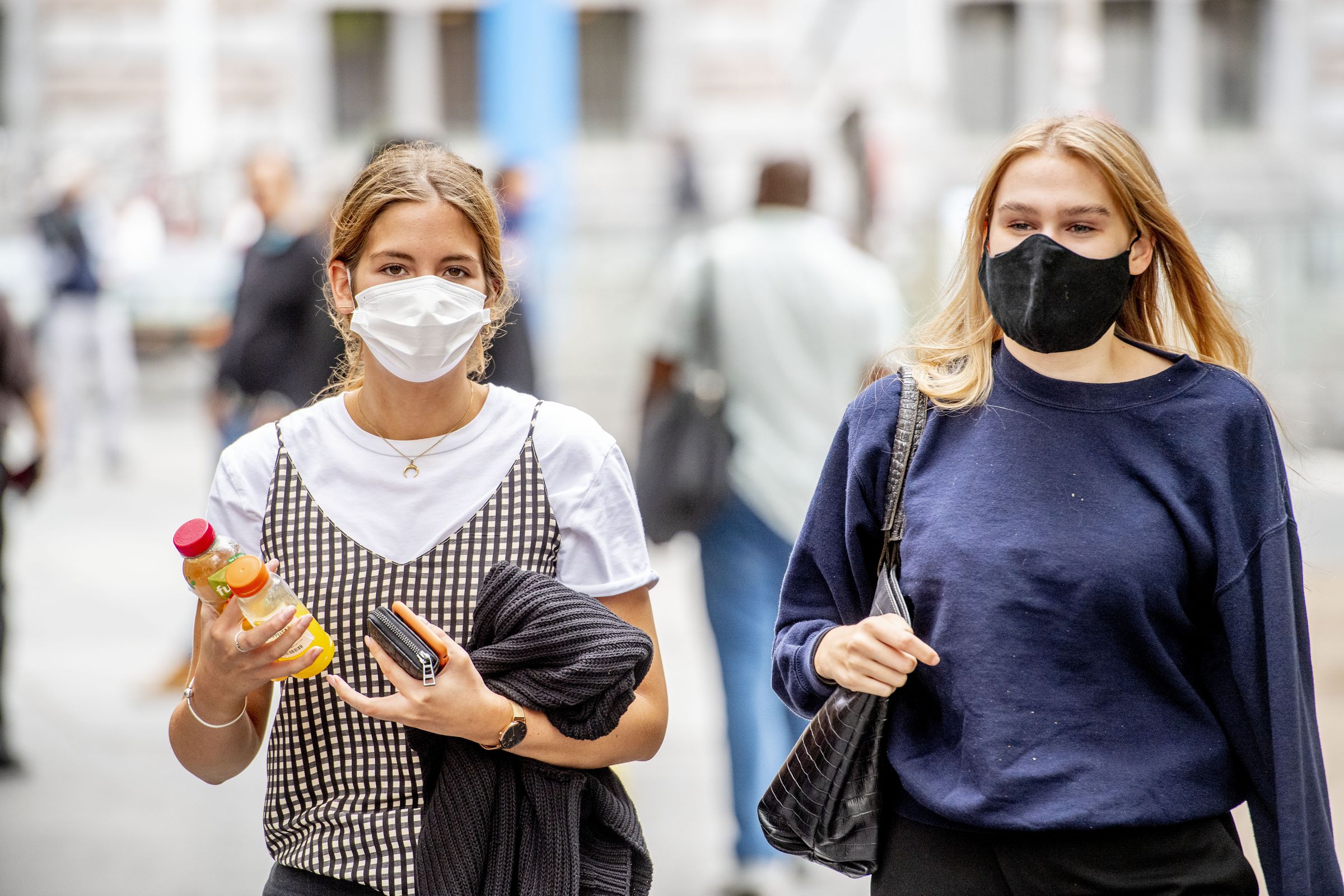 People wearing face masks as a preventive measure walk on...