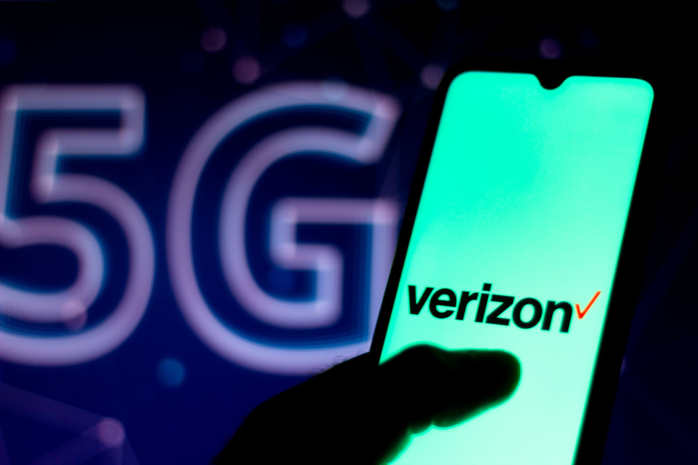 In this photo illustration the Verizon Communications logo seen displayed on a smartphone with the 5G inscription background.