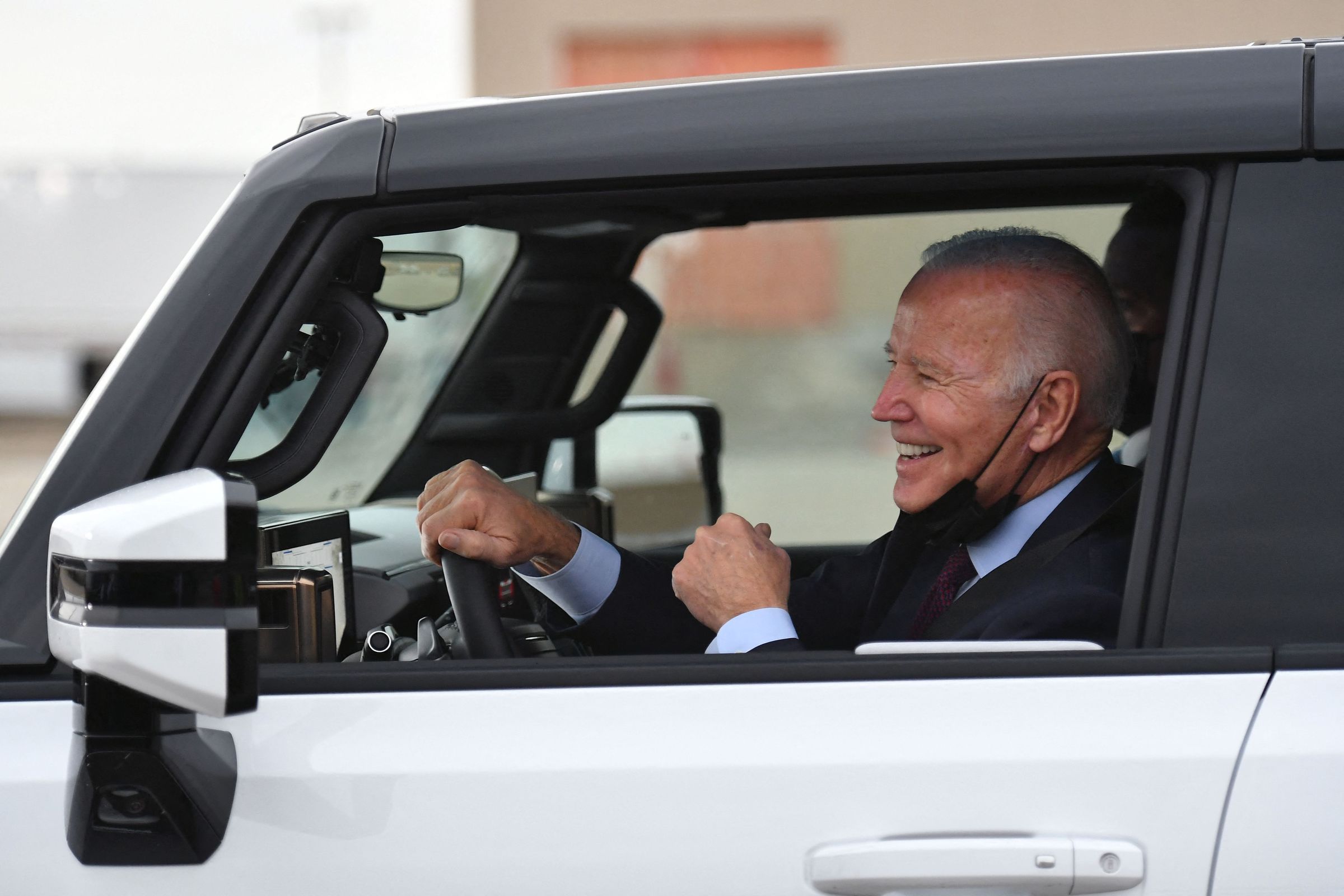 A photo of President Joe Biden smiling behind the wheel of a car