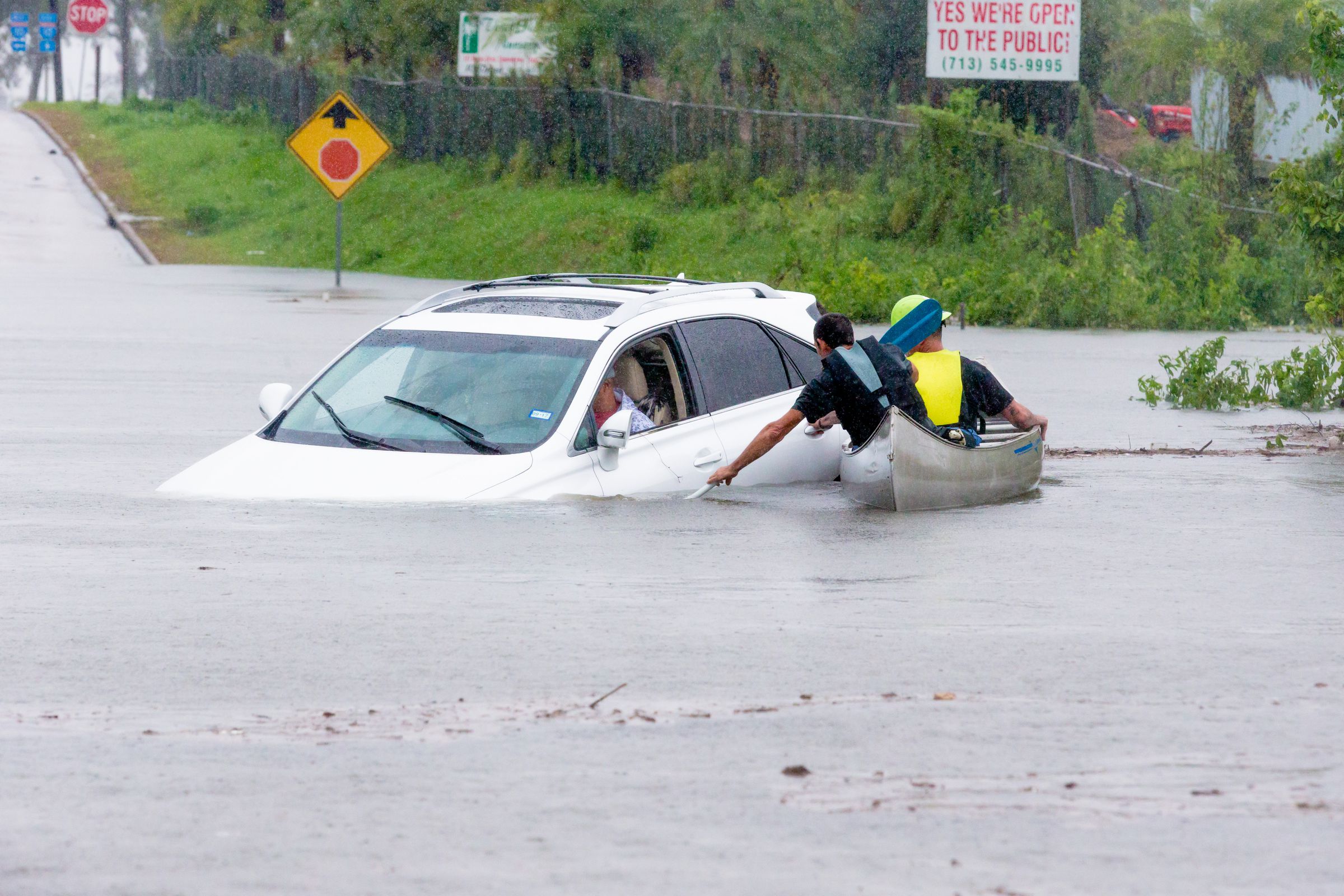 Volunteers in a canoe makes their way to assist a driver that was stalled going through high water during Hurricane Harvey, Monday, August 29, 2017.