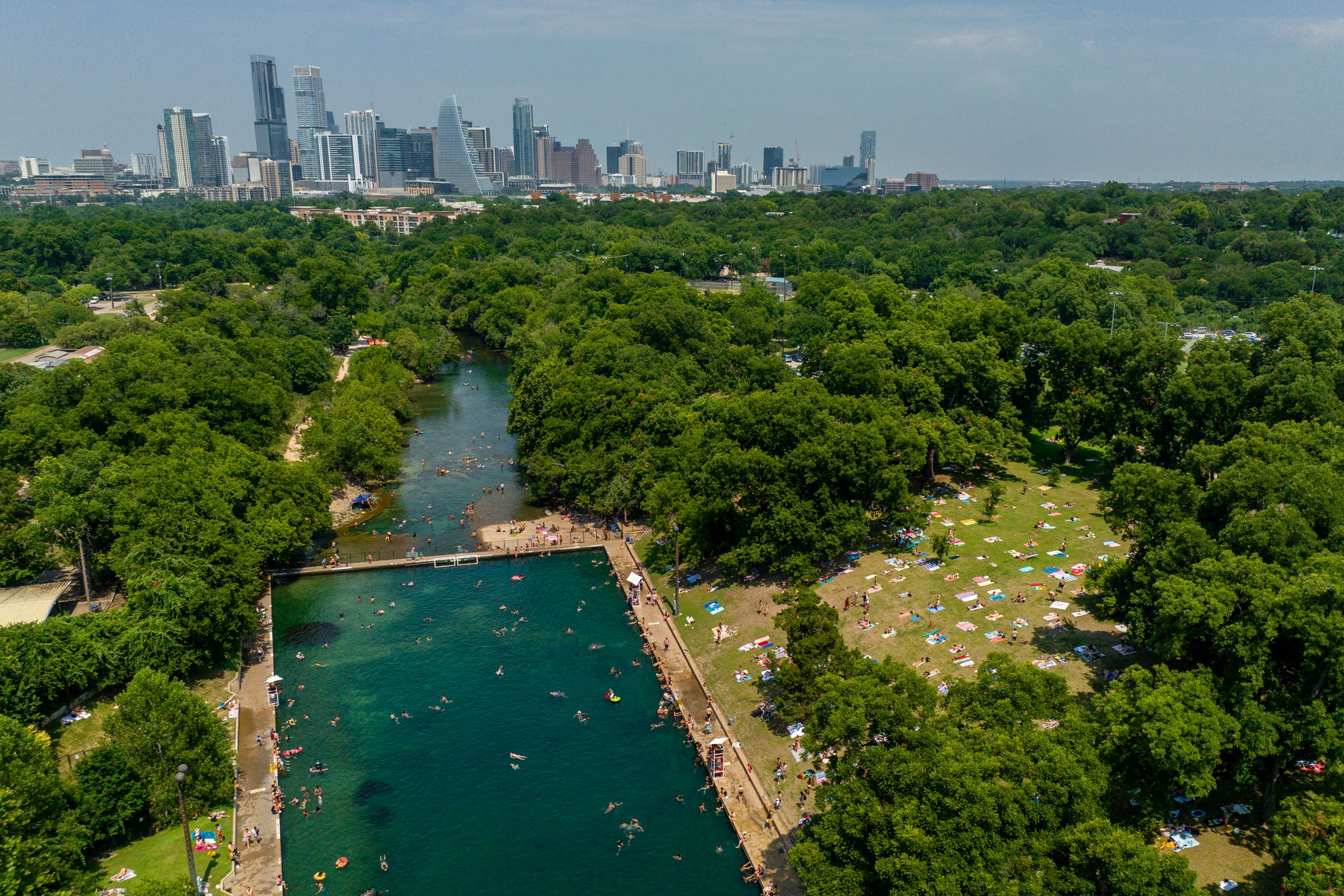 An aerial photograph of the Austin skyline next to a large, green park with a pool.