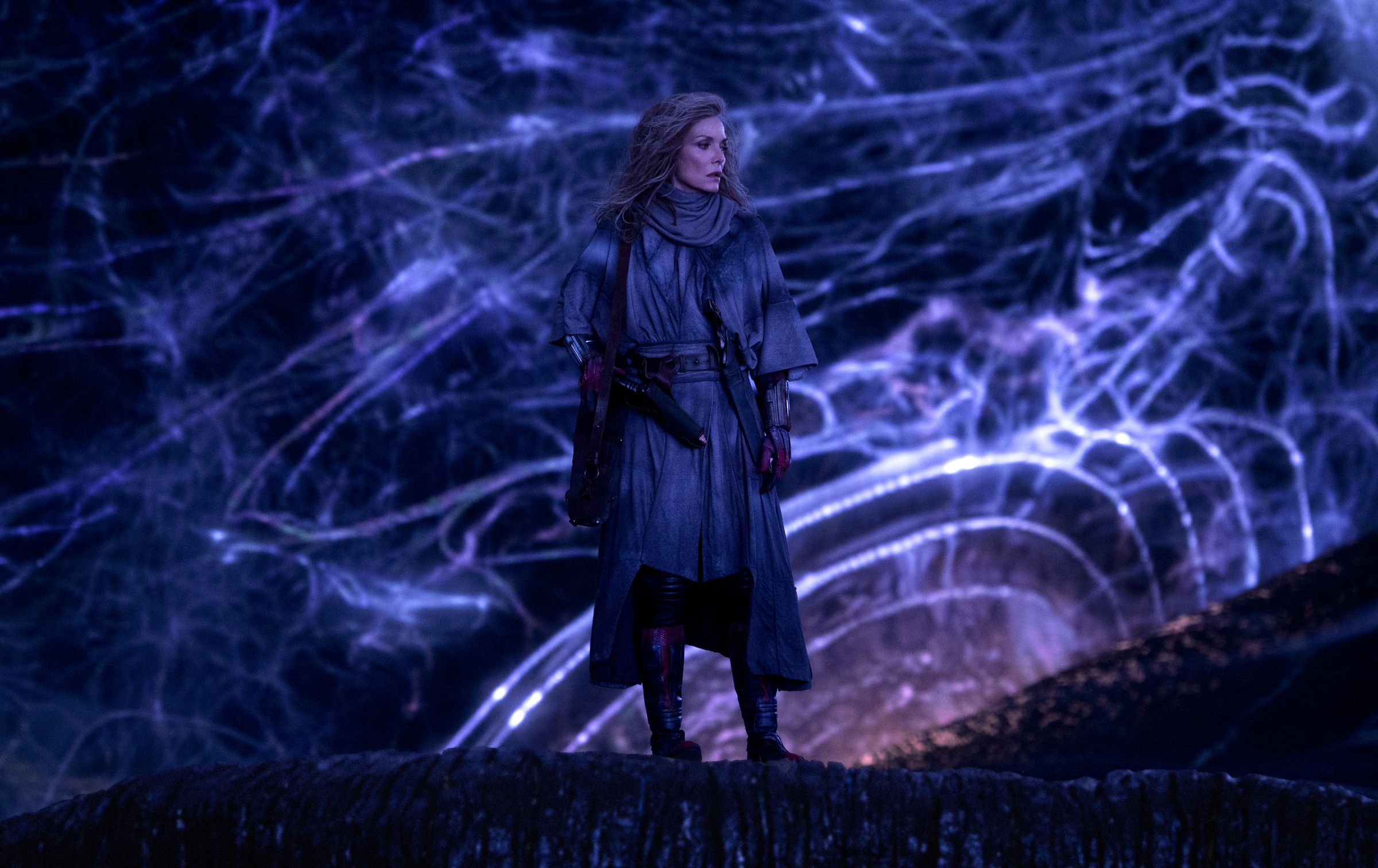 An image of Michelle Pfeiffer as the Wasp, standing in front of a messy glowing purple background.