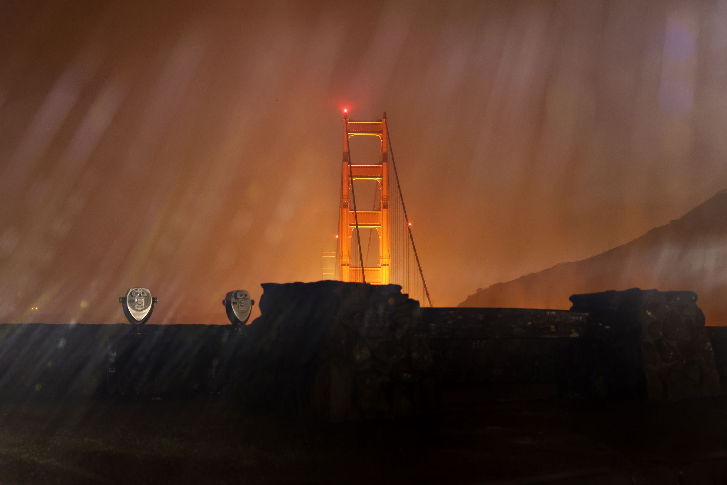 The Golden Gate Bridge is seen lit up at night in the rain.