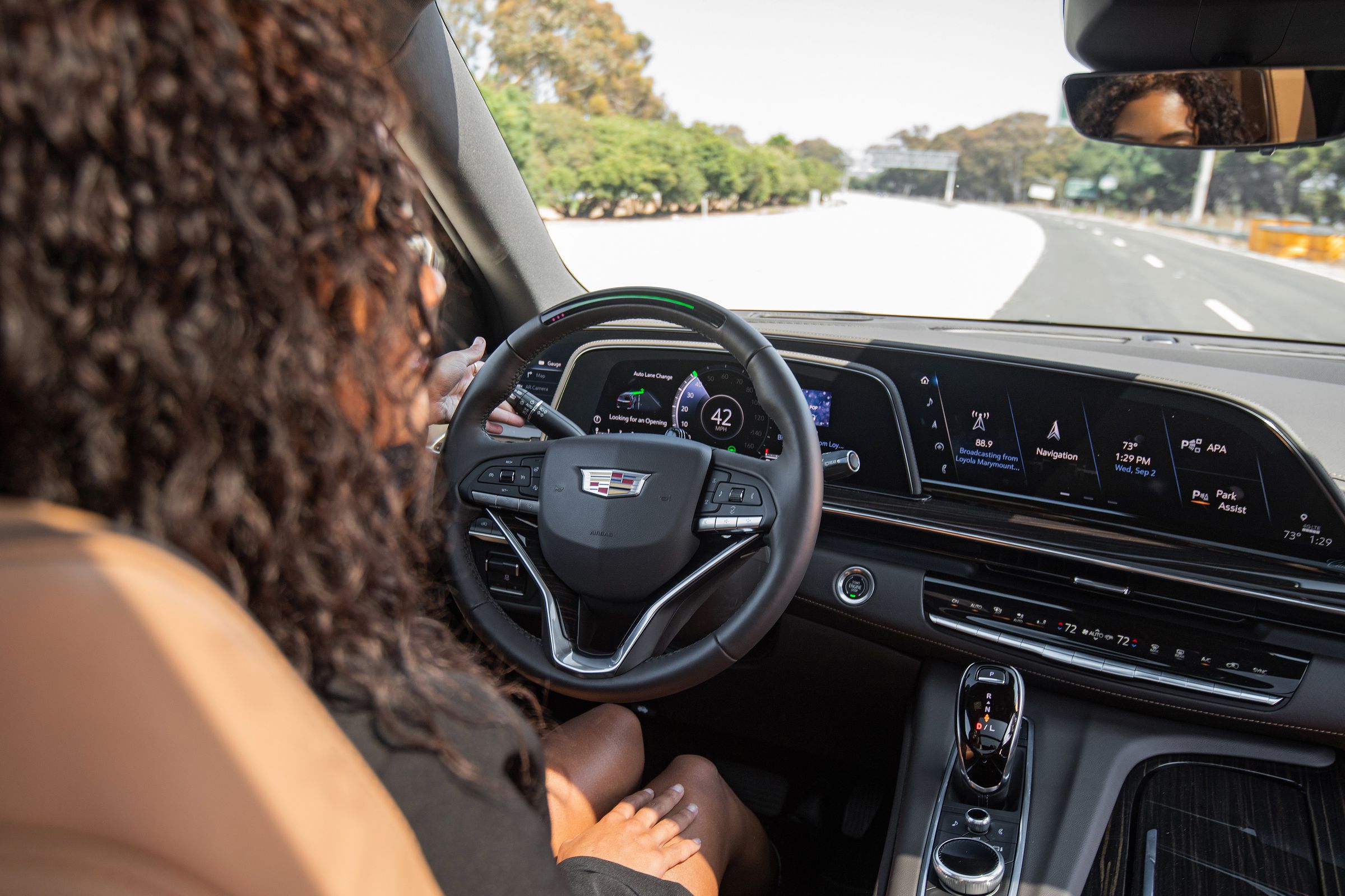 Over-the-shoulder shot of a woman using Super Cruise, GM’s hands-free driver assistance technology, in a Cadillac Escalade.