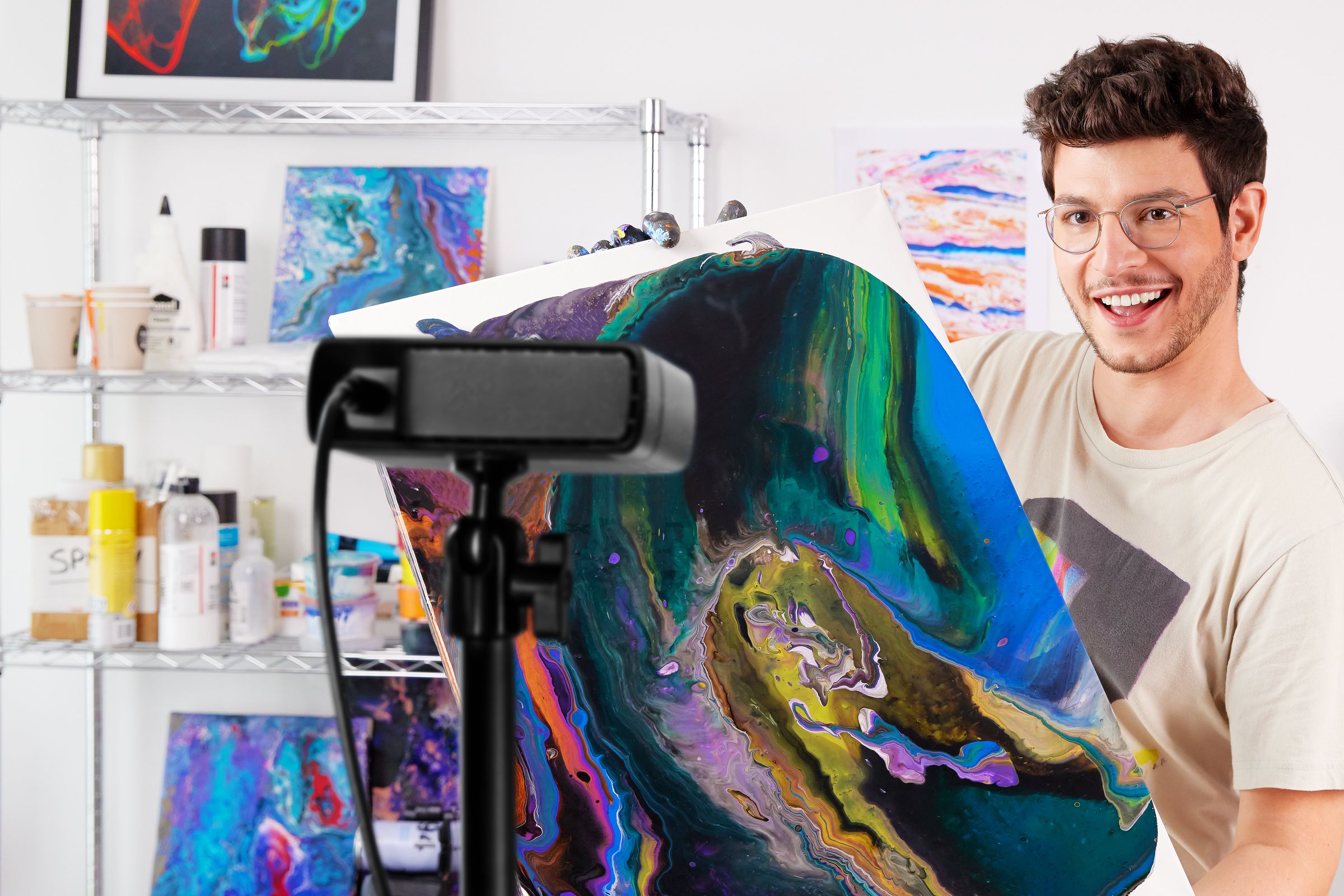 The Elgato Facecam Pro webcam is mounted to a tripod, facing someone who’s showing off their artwork.