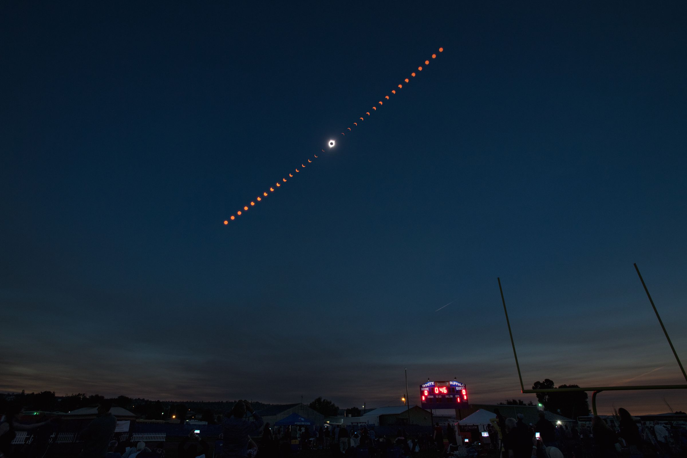 Different phases of a solar eclipse — ranging from a crescent to a complete eclipse — seen over a dark sky.