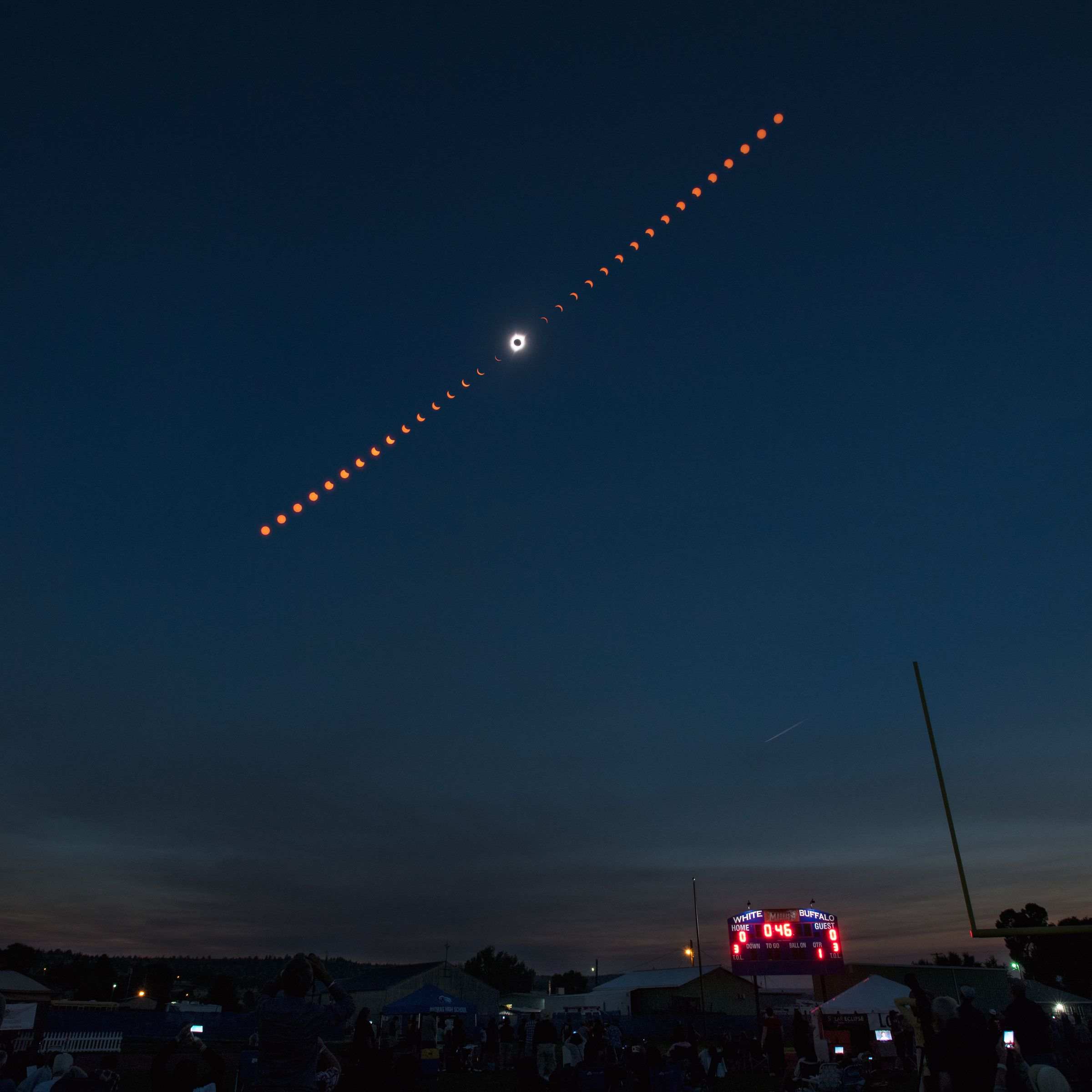Different phases of a solar eclipse — ranging from a crescent to a complete eclipse — seen over a dark sky.