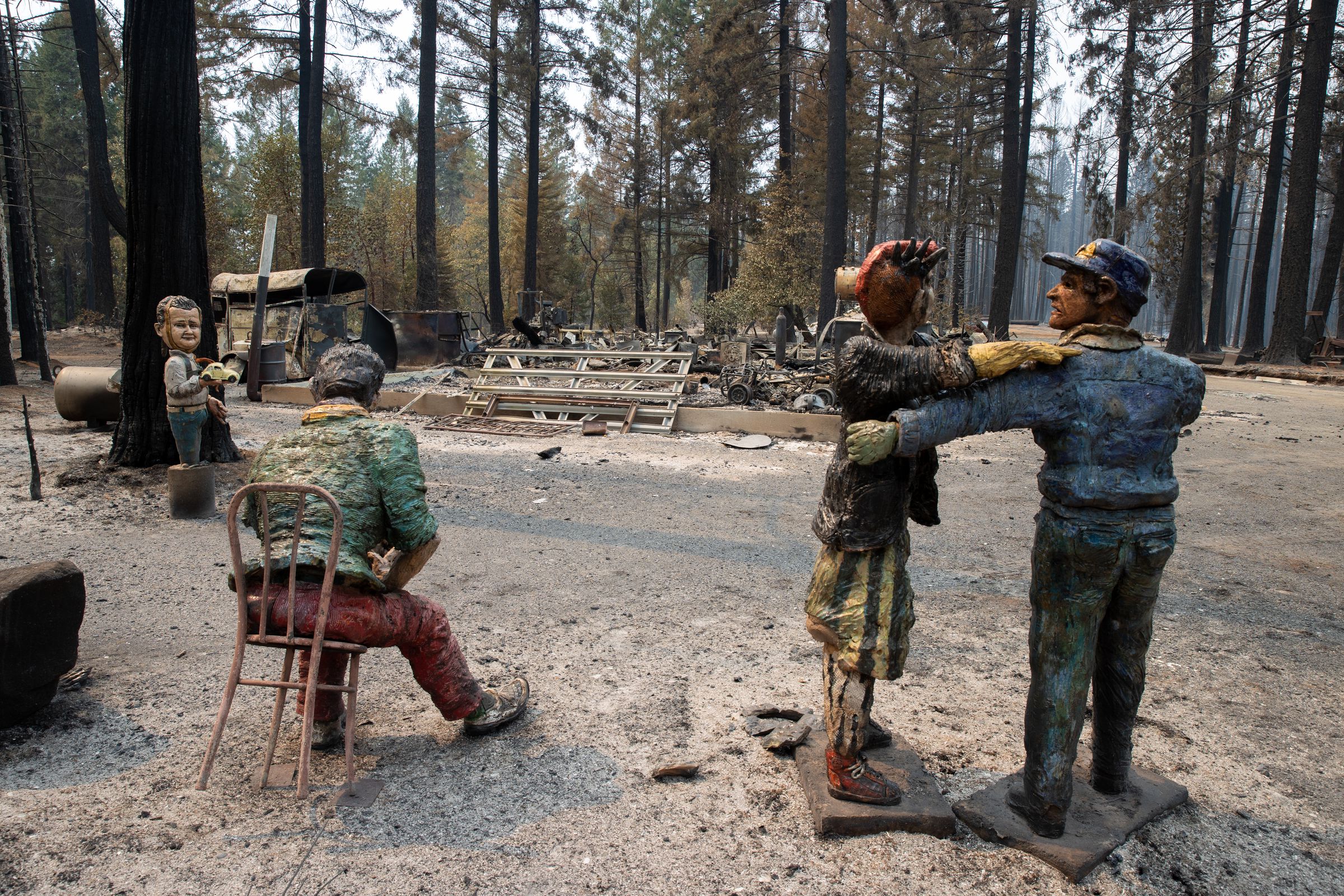 Statues of people are left behind amid the ruins of structures burned by the Mosquito Fire.