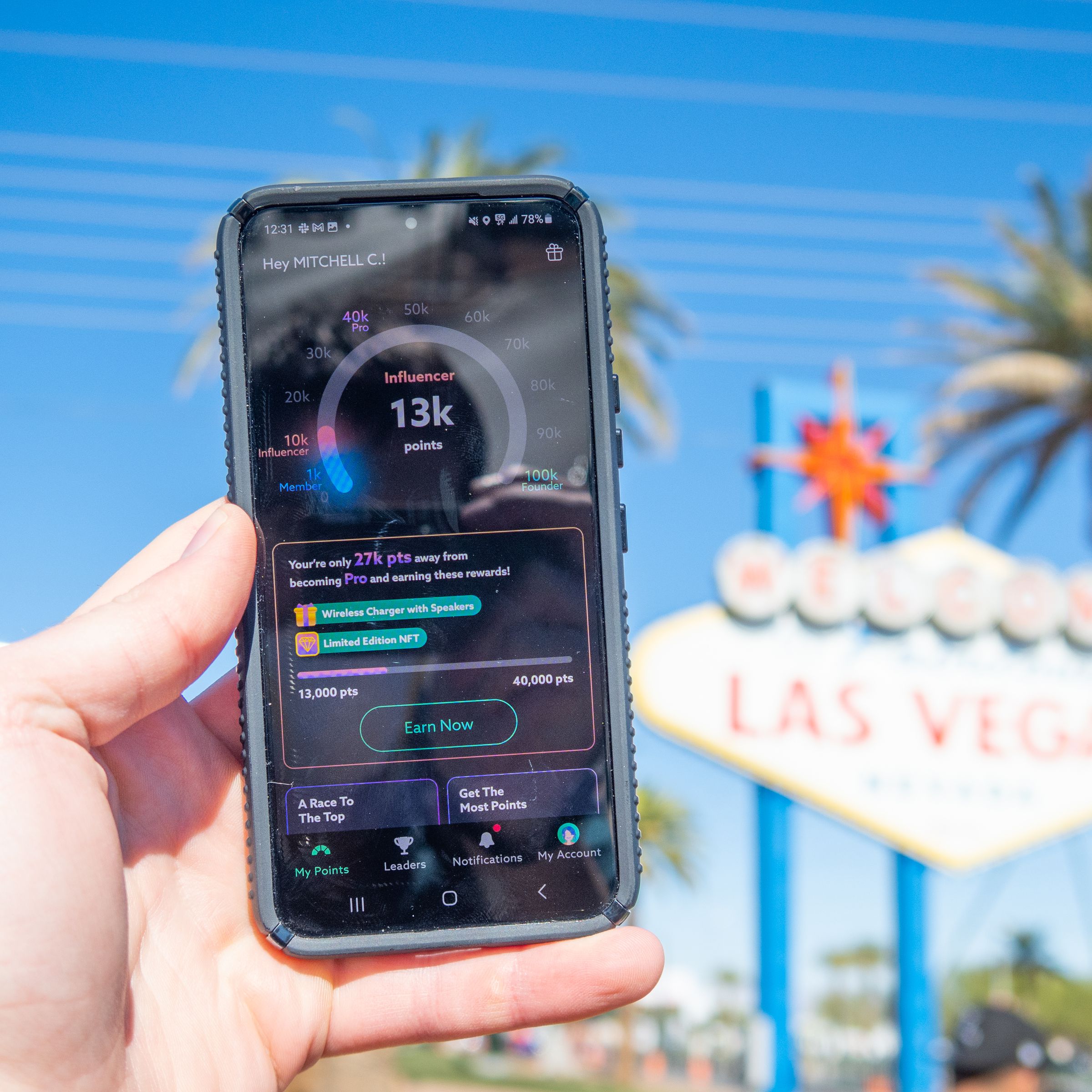 Photo of a hand holding a phone running the Project Genesis app in front of the Welcome to Las Vegas sign.