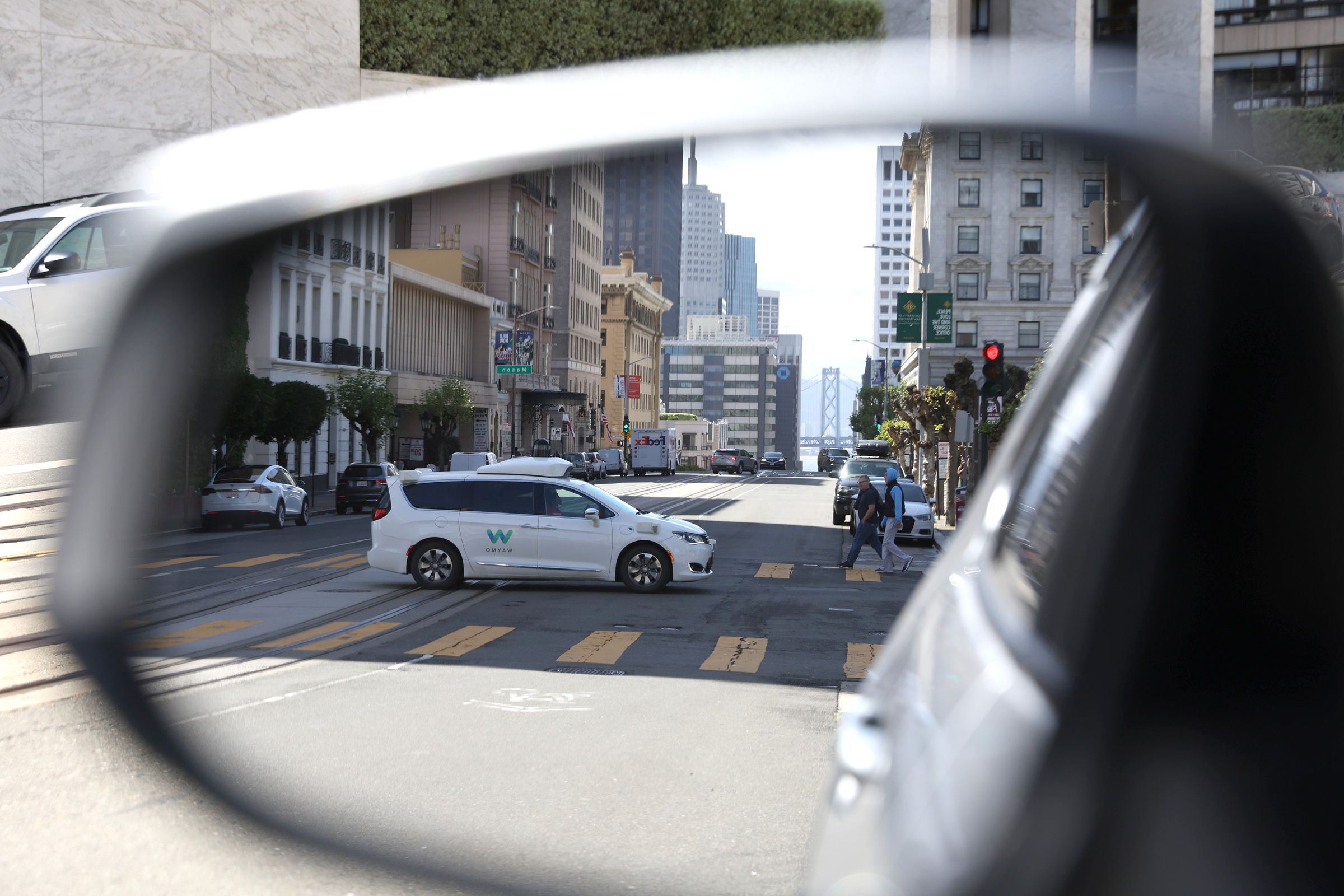 A Waymo autonomous vehicle is seen reflected in a mirror as it drives along California Street in San Francisco