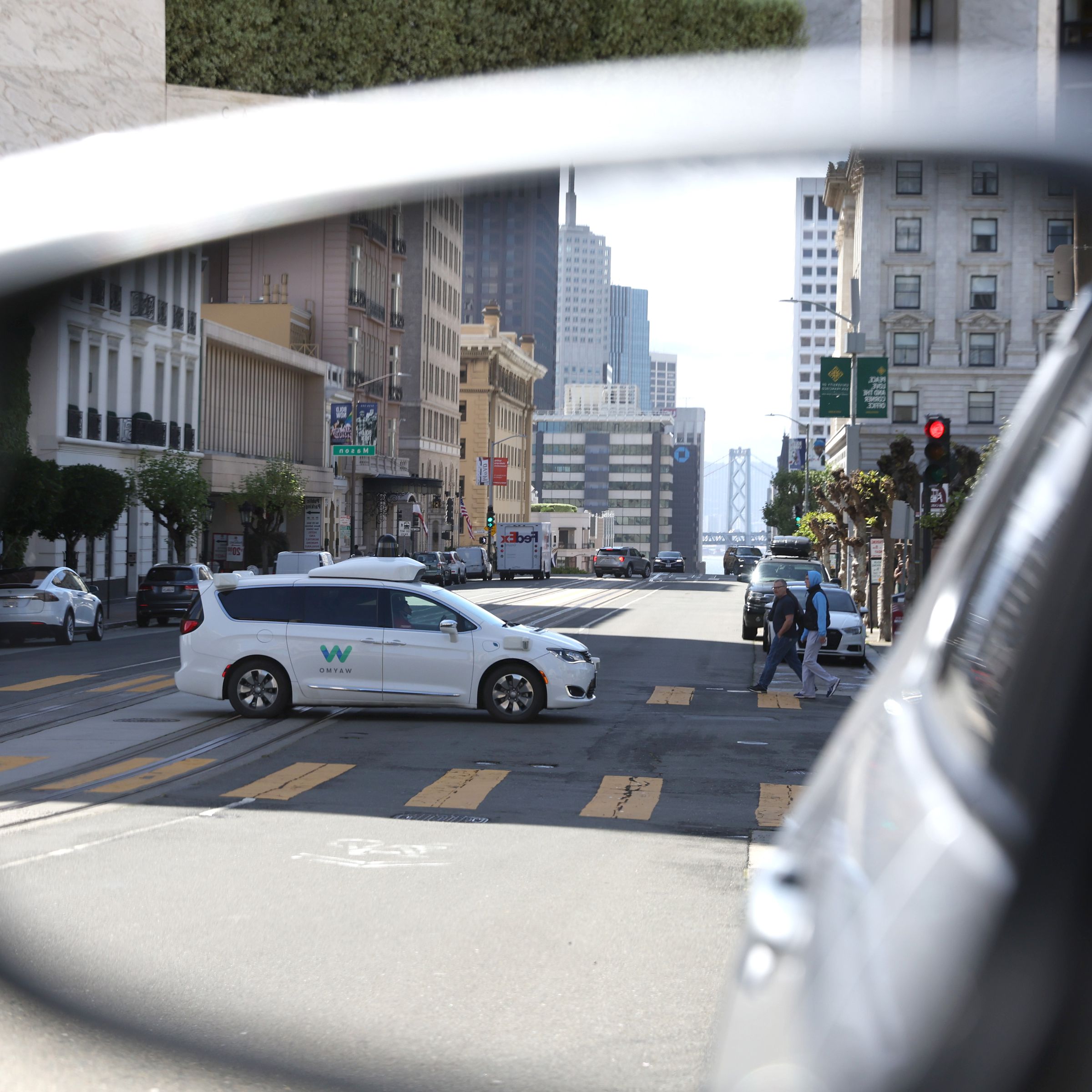 A Waymo autonomous vehicle is seen reflected in a mirror as it drives along California Street in San Francisco