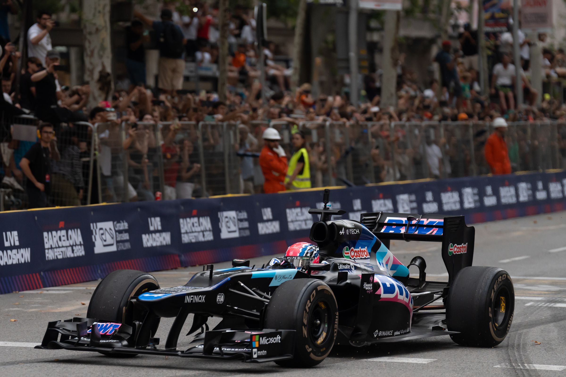 An F1 car driving on a track, with a crowd behind it.