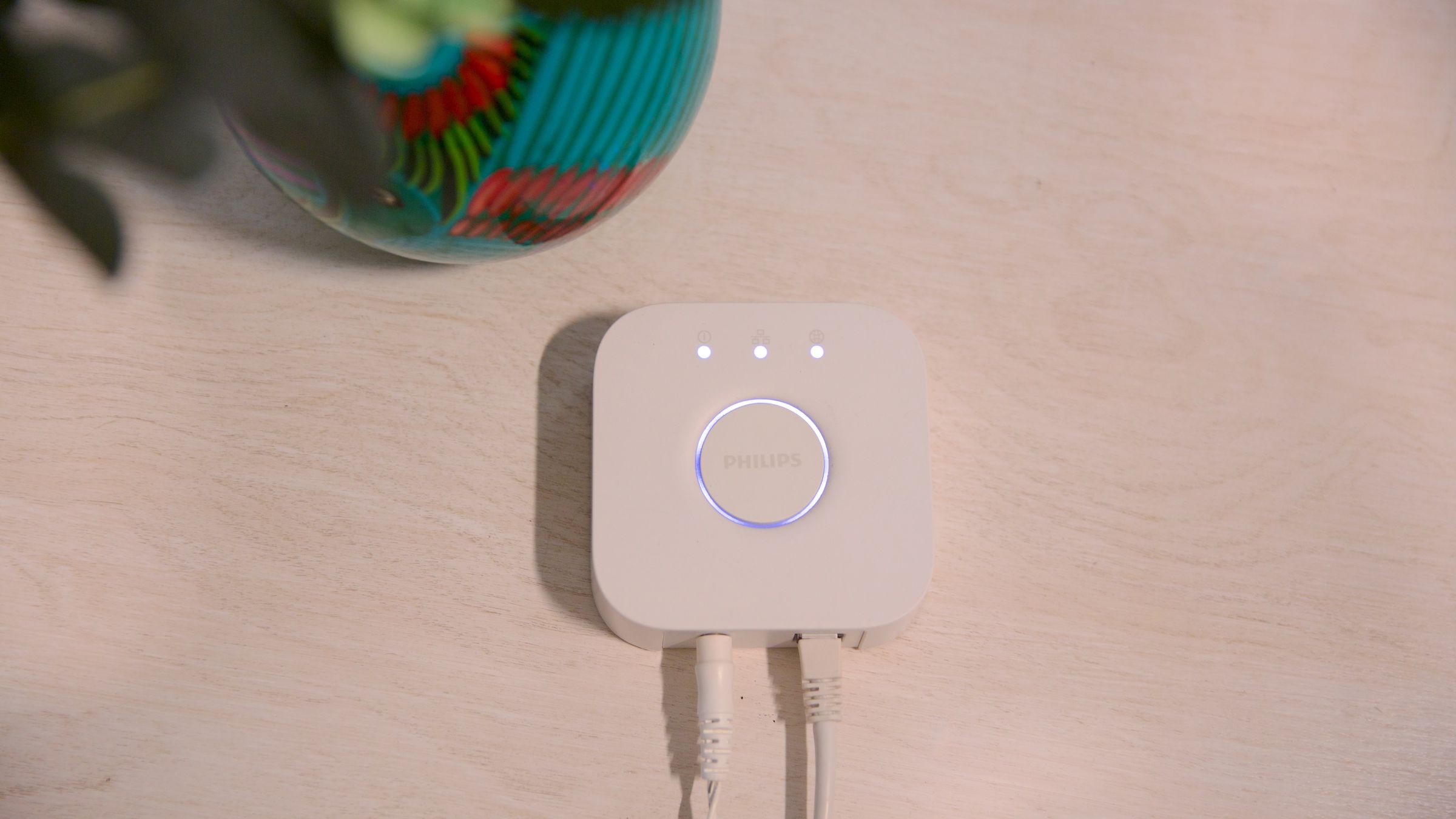 A white Philips Hue bridge on a white countertop.