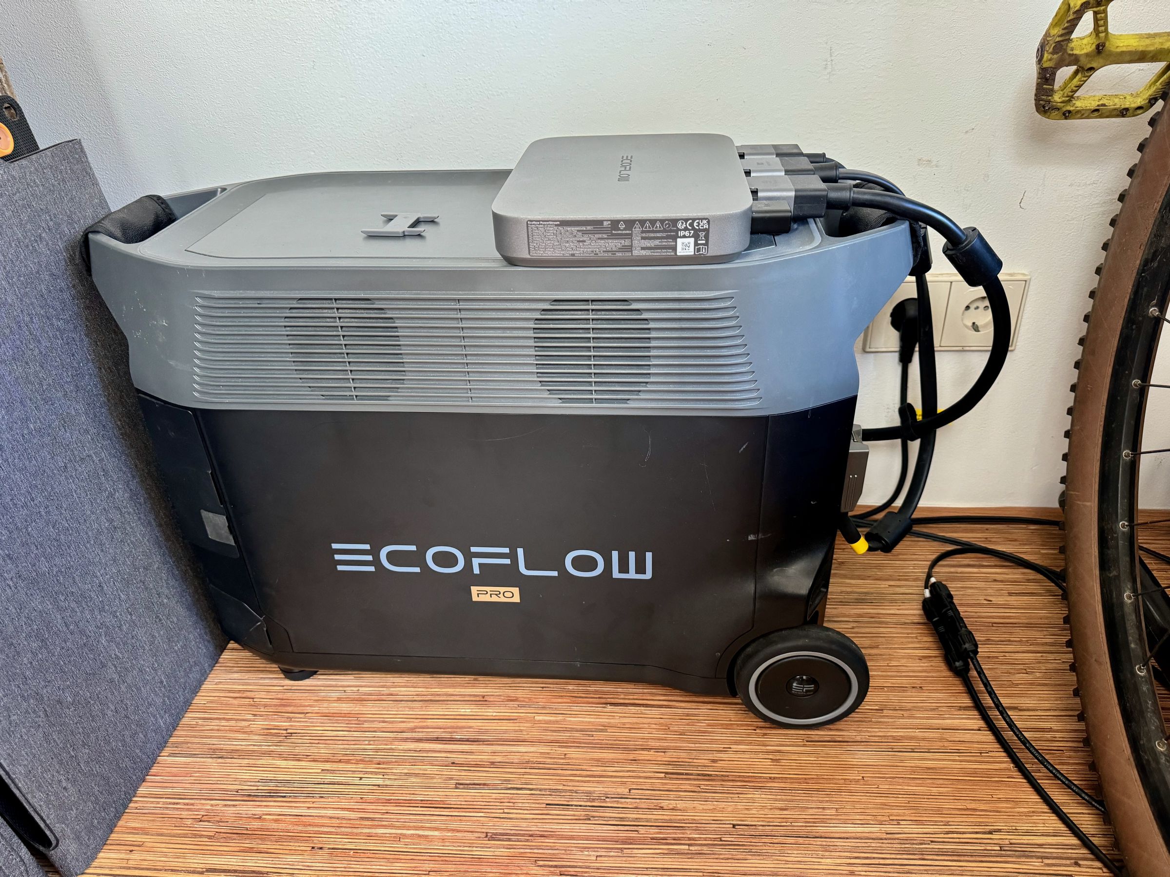 <em>The PowerStream sitting on top of an EcoFlow Delta Pro solar generator. Three connections run out of the PowerStream: one to the wall jack; one to the Delta Pro battery; and one to the solar panels installed far away on the roof.</em>
