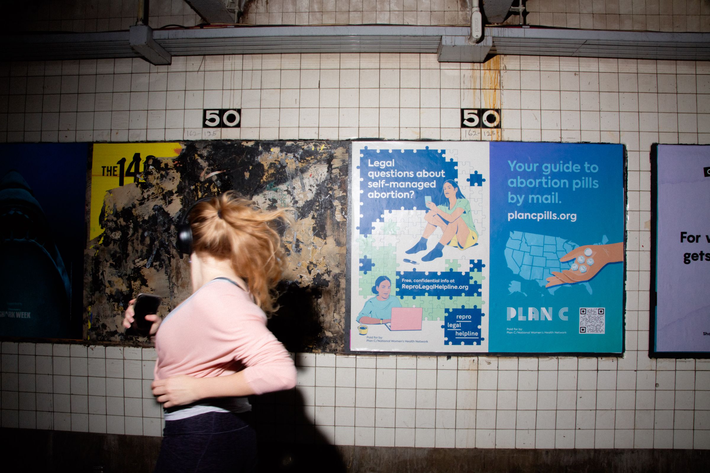A woman running by an advertisement for Plan C in the New York City subway.